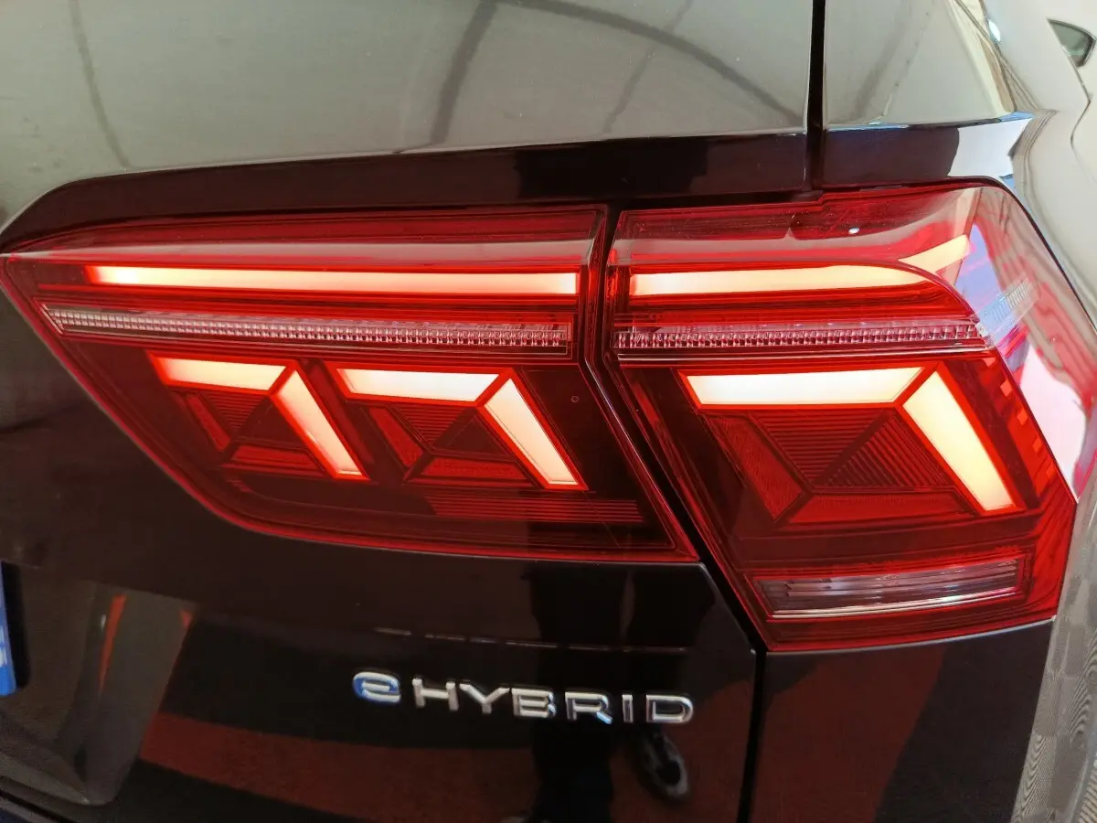 Gros plan sur le feu arrière droit rouge et blanc d’un Volkswagen Tiguan noir eHYBRID 2023.