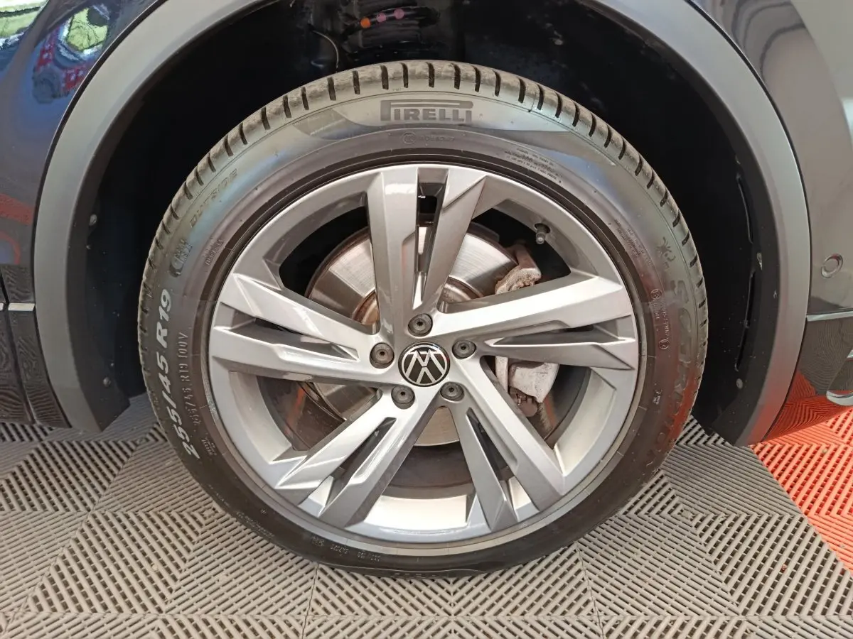 Gros plan sur la roue avant droite du Volkswagen Tiguan noir, mettant en valeur la jante alliage et le pneu Pirelli.