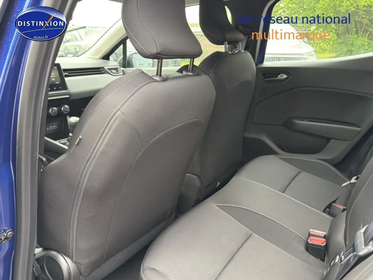 Vue intérieure arrière côté gauche de la Renault Clio V bleu iron, montrant la banquette et le dossier des sièges avant noirs.