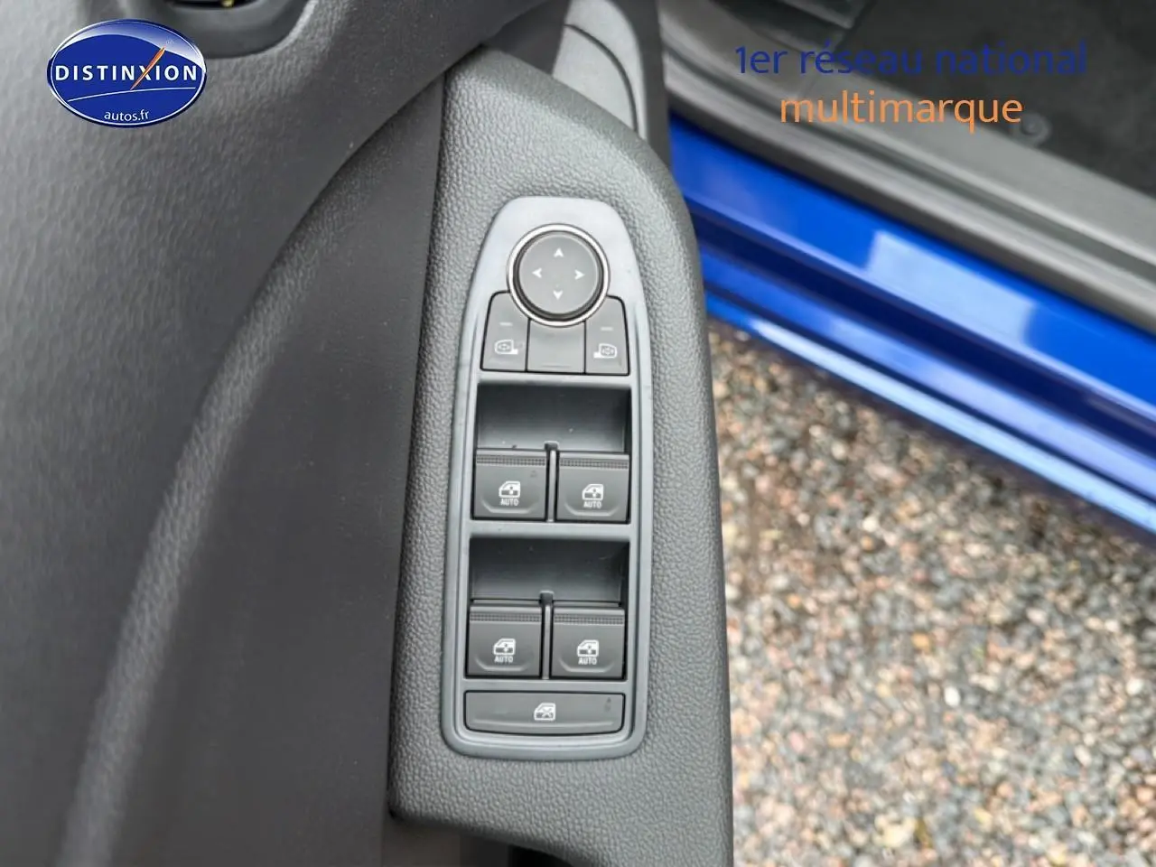 Vue rapprochée des commandes des vitres côté gauche sur porte bleu iron d’une Renault Clio V 1.0 TCe 90 Evolution.