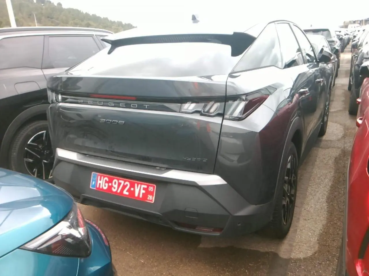 Vue 3/4 arrière d'un Peugeot 3008 2025 gris foncé avec jantes alliage 19'' noir brillant sur un parking.