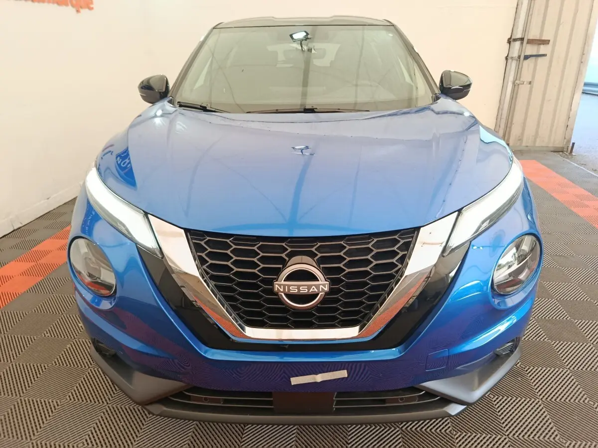 Vue frontale d'un Nissan Juke bleu 2025 avec calandre hexagonale noire et détails chromés brillants.