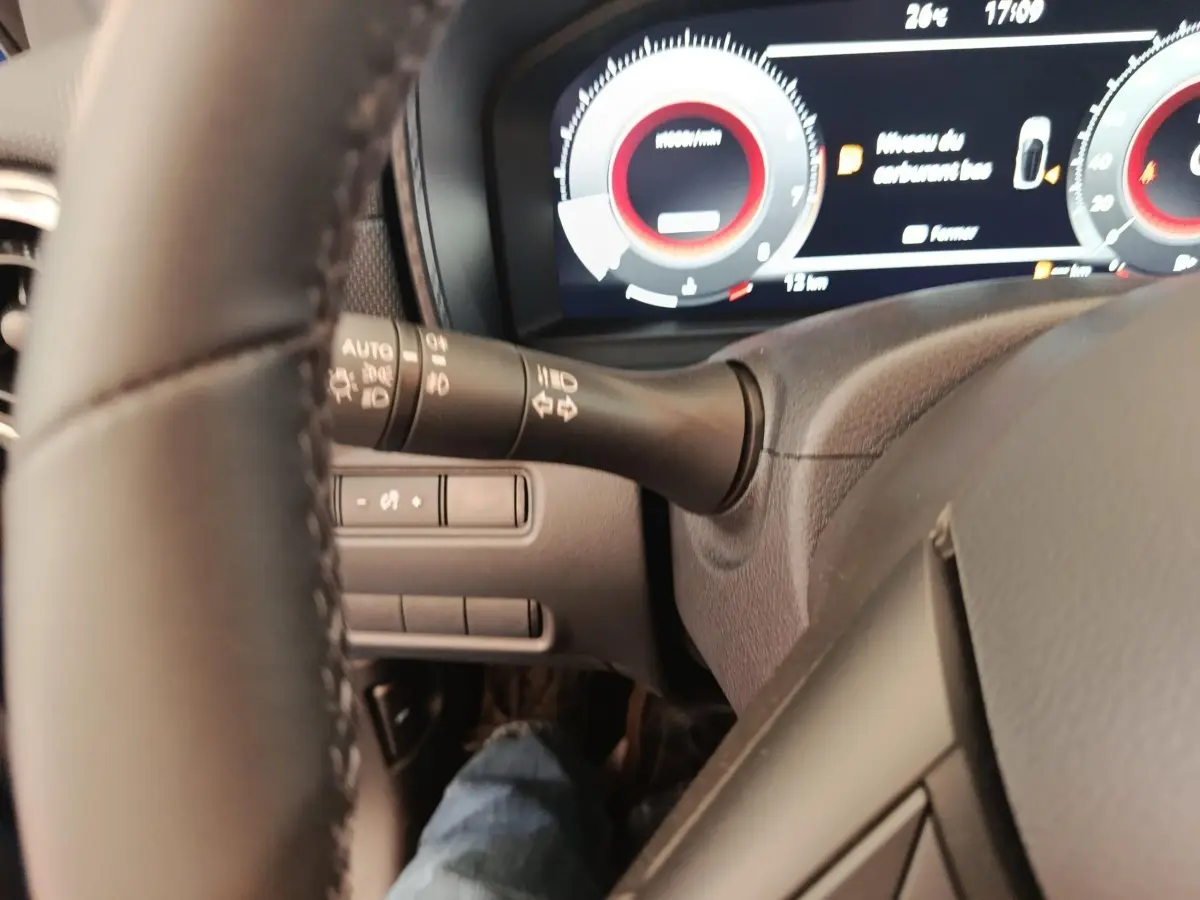 Vue rapprochée du tableau de bord et du volant noir du Nissan Juke 2025, affichage numérique avec compte-tours rouge.
