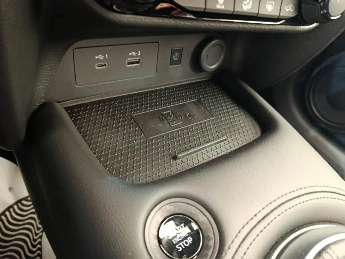 Gros plan sur la console centrale noire du Nissan Juke bleu 2025, avec bouton start/stop et ports USB visibles.