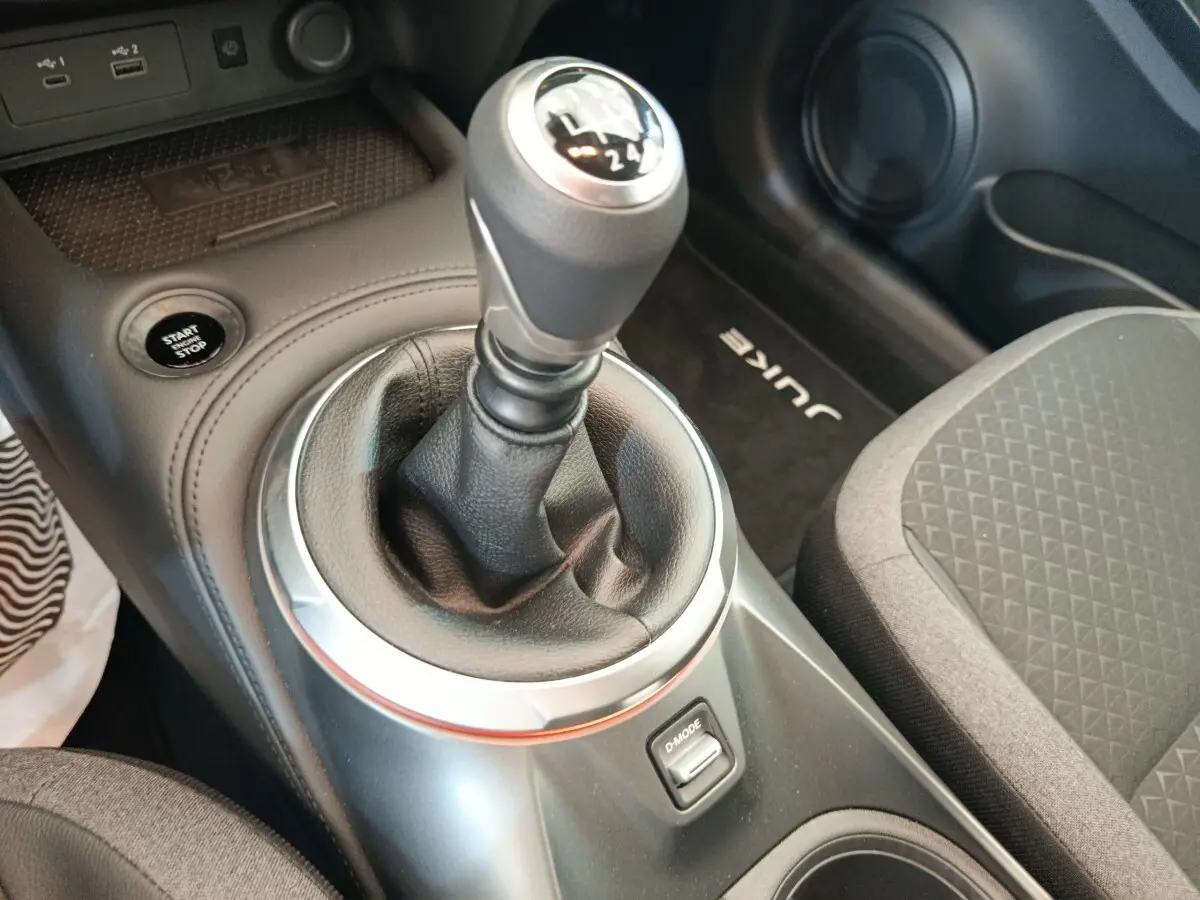 Gros plan sur la boîte manuelle et le bouton start/stop dans l’habitacle noir du Nissan Juke 2025.