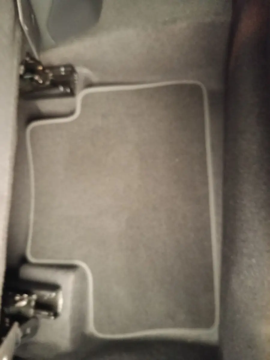 Vue rapprochée du tapis de sol gris foncé à bordures claires dans l'habitacle du Nissan Juke bleu 2025.