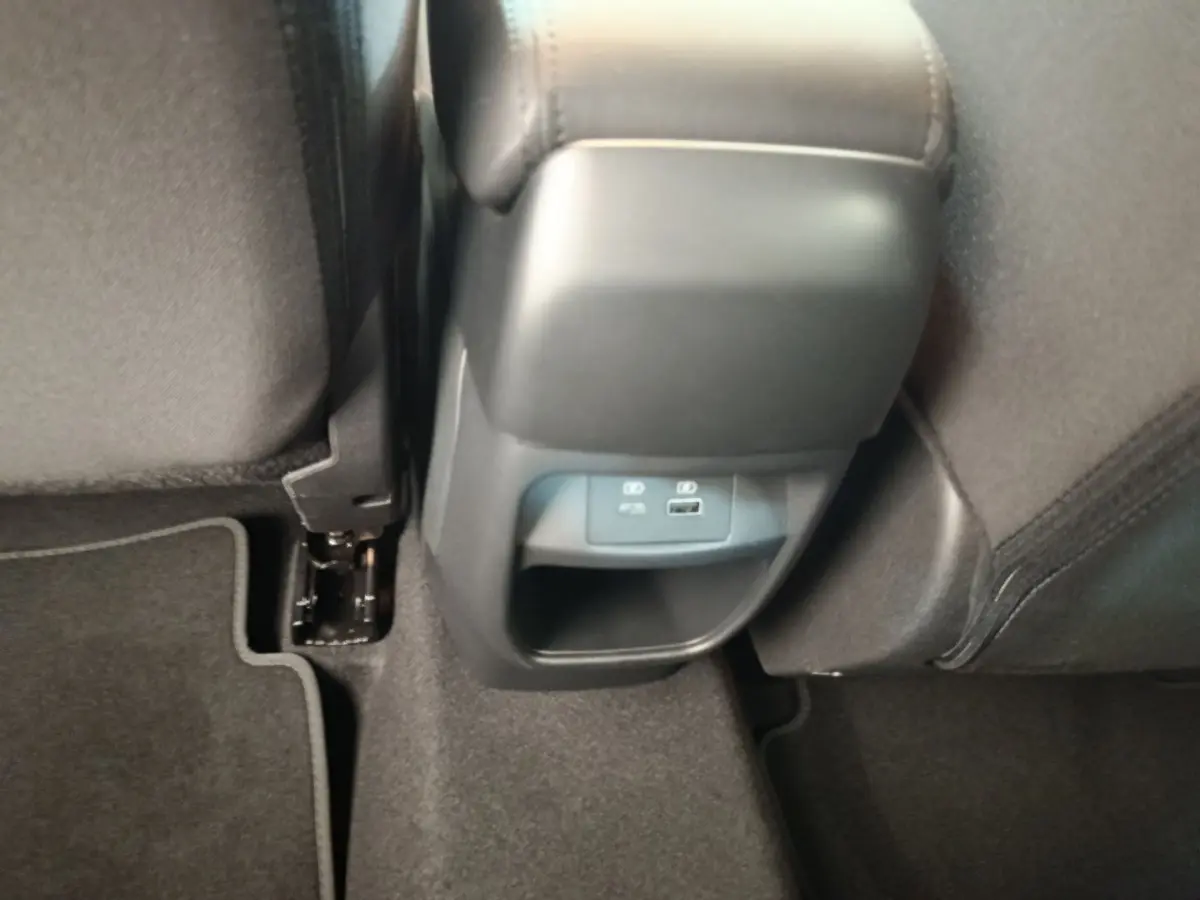 Vue rapprochée de la console arrière noire avec prises USB et éclairage, entre les sièges arrière tissu gris du Nissan Juke bleu.