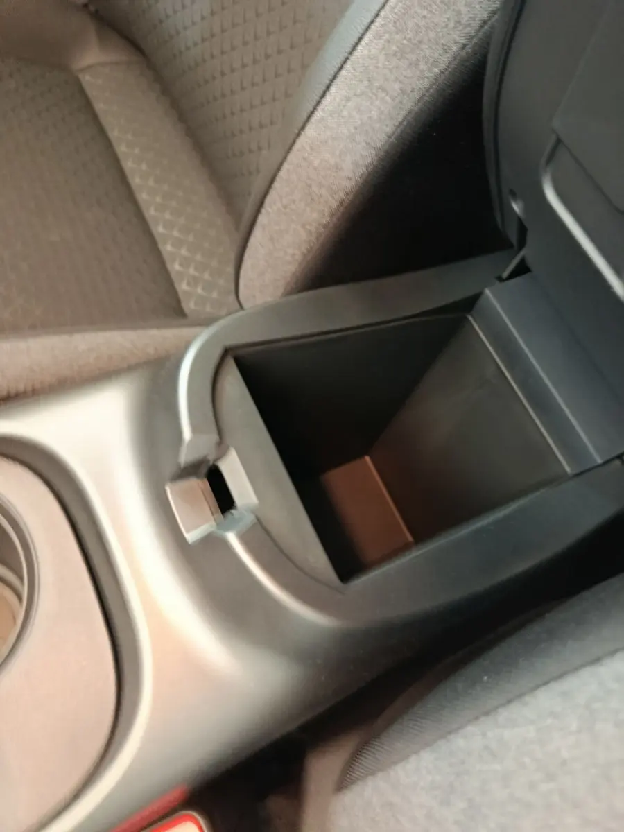Vue rapprochée de l'accoudoir central avant ouvert du Nissan Juke bleu, montrant le rangement intérieur vide.