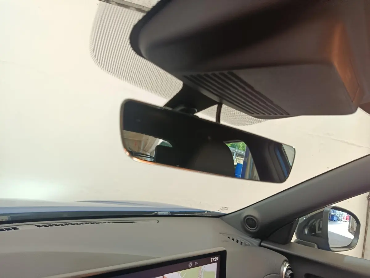 Vue intérieure du tableau de bord du Nissan Juke bleu 2025, avec écran tactile de navigation et rétroviseur central visible.