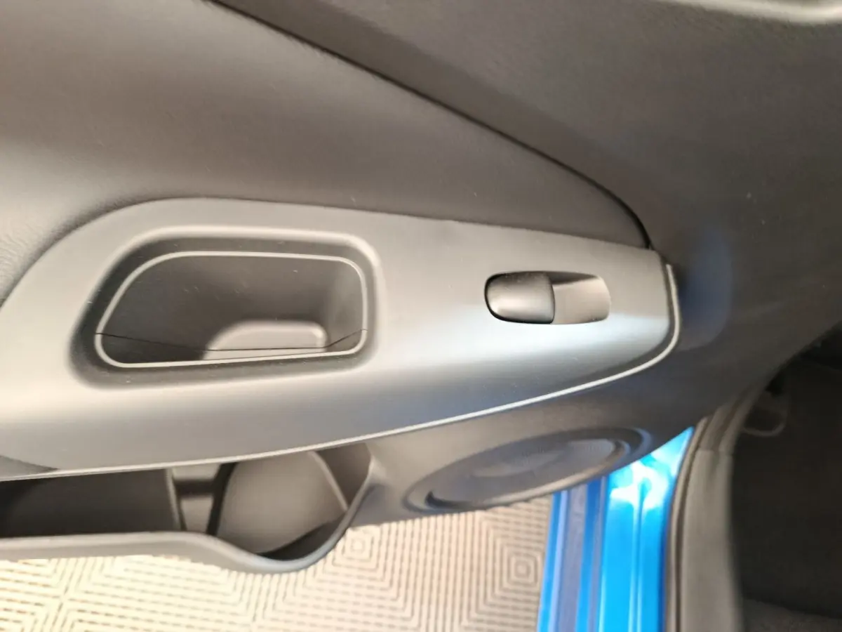 Poignée intérieure et commande de verrouillage sur la porte côté gauche d’un Nissan Juke bleu, vue rapprochée.