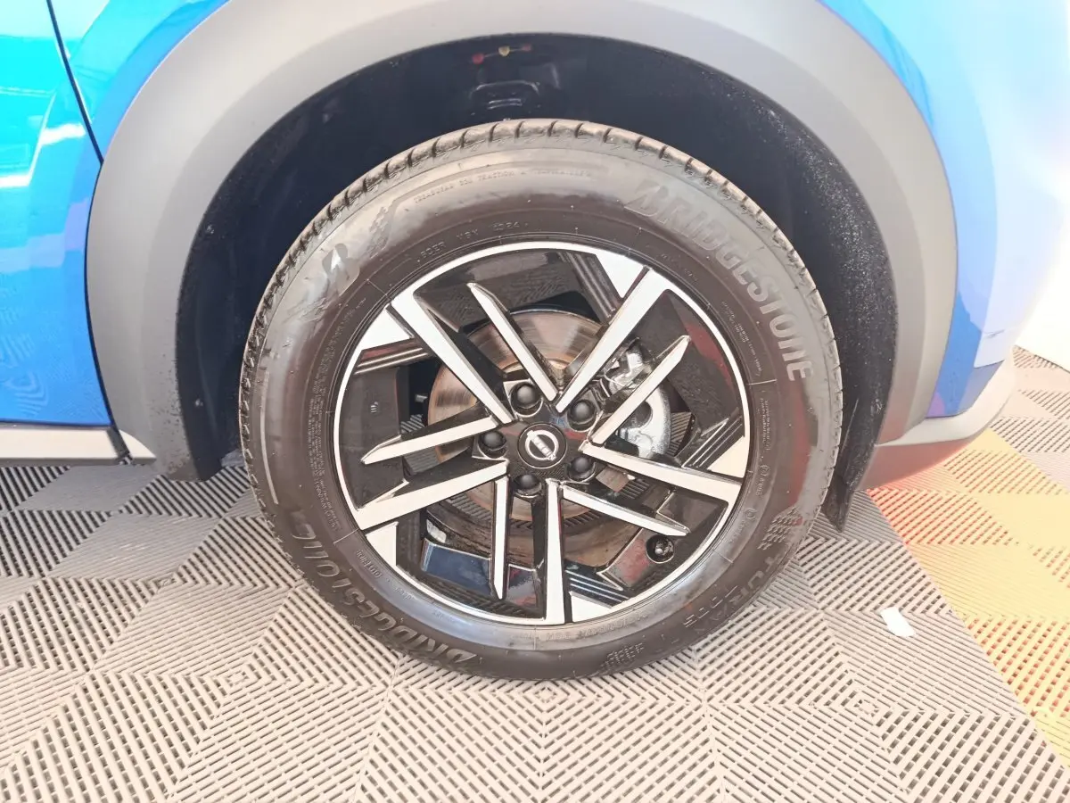 Gros plan sur la roue avant droite du Nissan Juke bleu 2025 avec jante alliage noir et argentée.