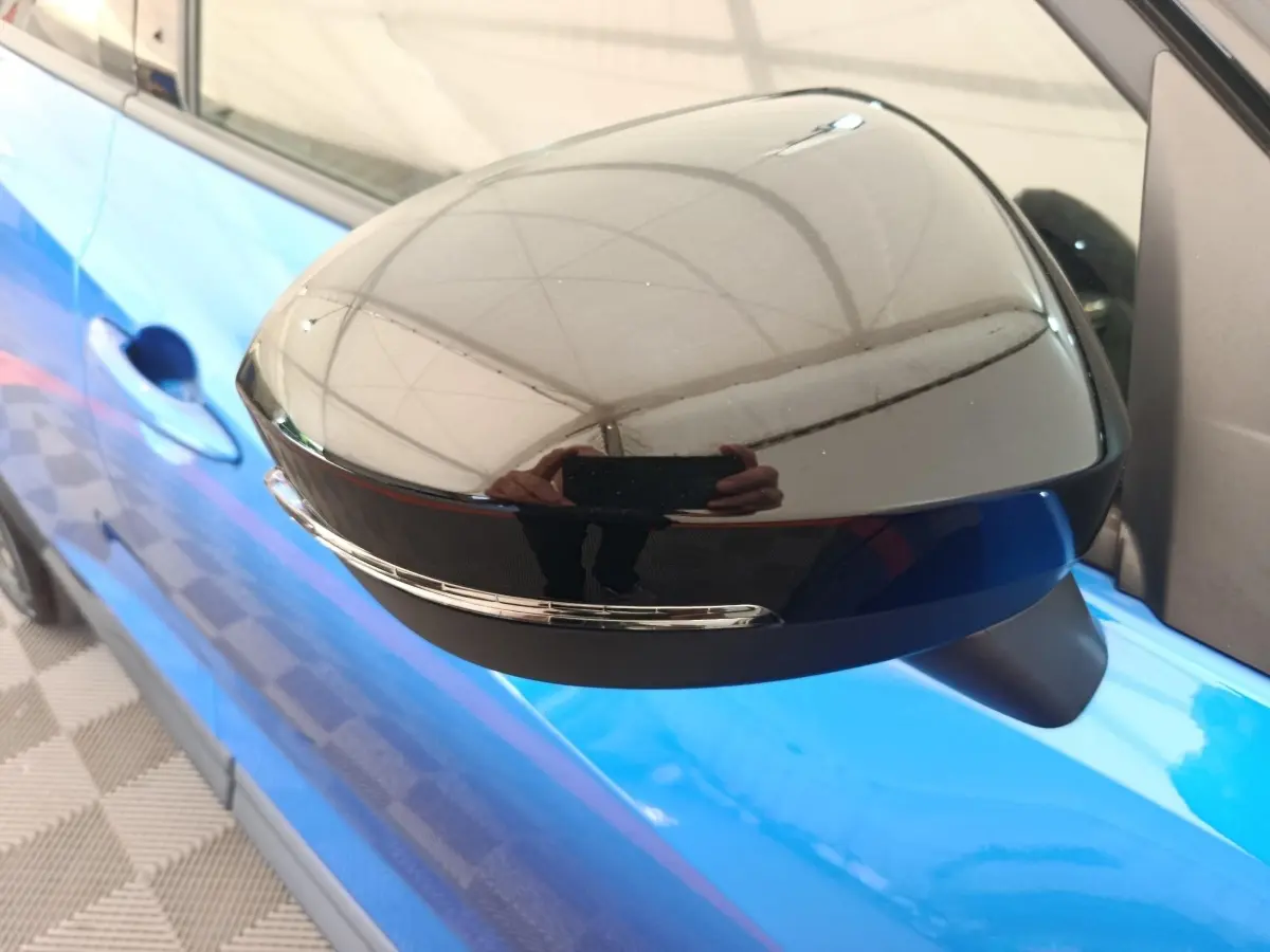 Rétroviseur côté gauche noir brillant avec clignotant intégré sur Nissan Juke bleu vue rapprochée.