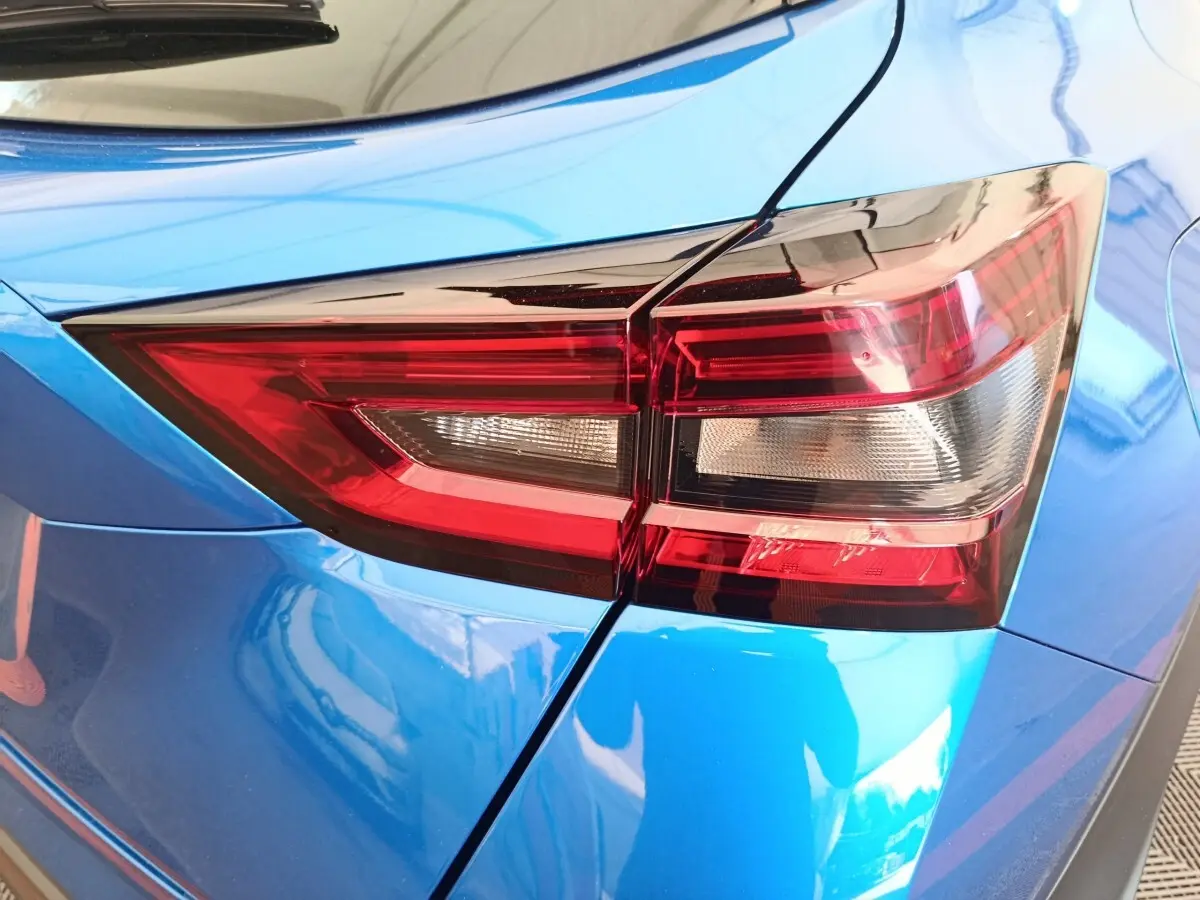 Gros plan sur le feu arrière droit rouge et blanc du Nissan Juke bleu 2025, soulignant la carrosserie brillante.