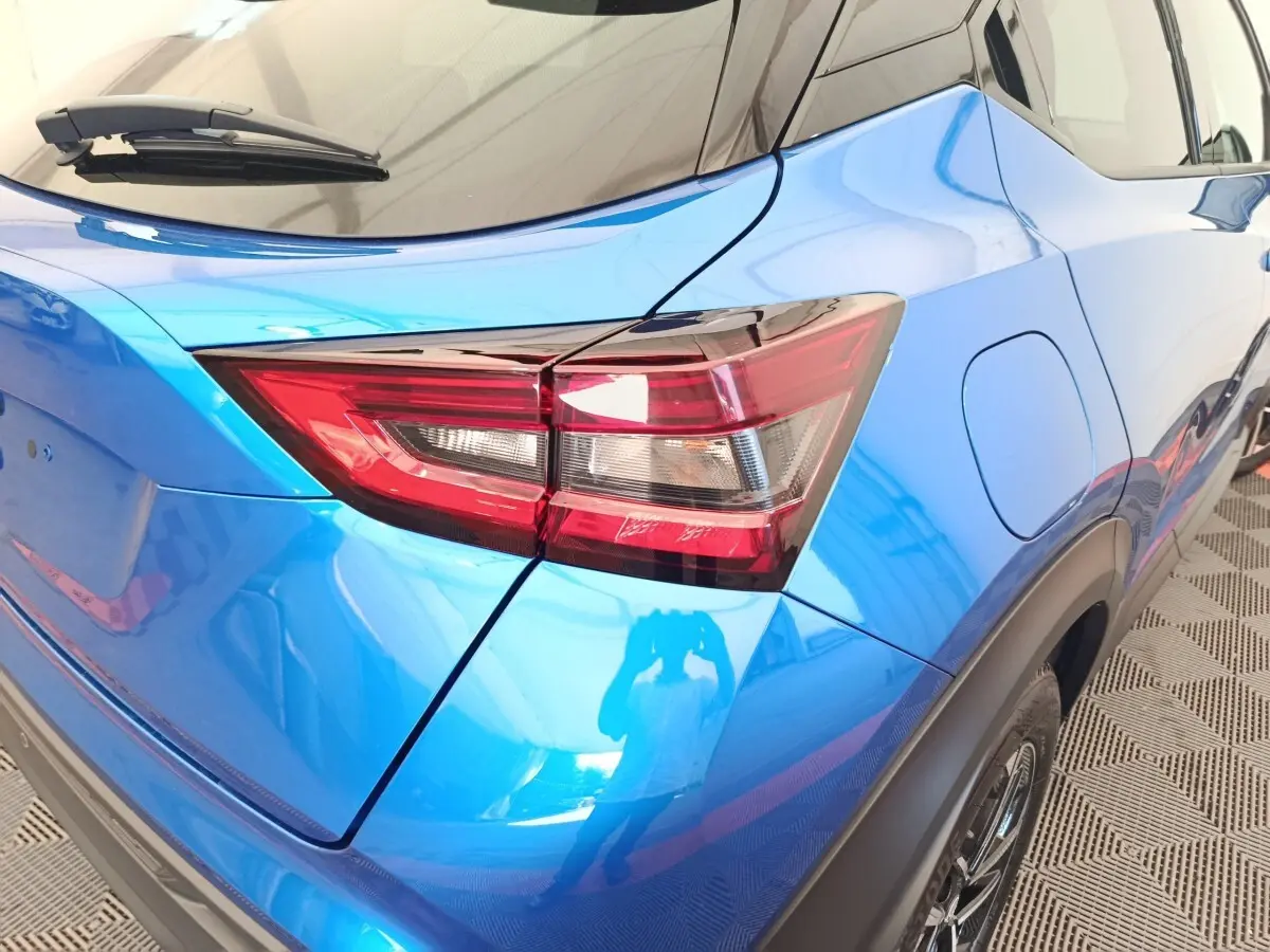 Vue 3/4 arrière droite du Nissan Juke bleu 2025, mettant en valeur le feu arrière et la trappe à carburant.
