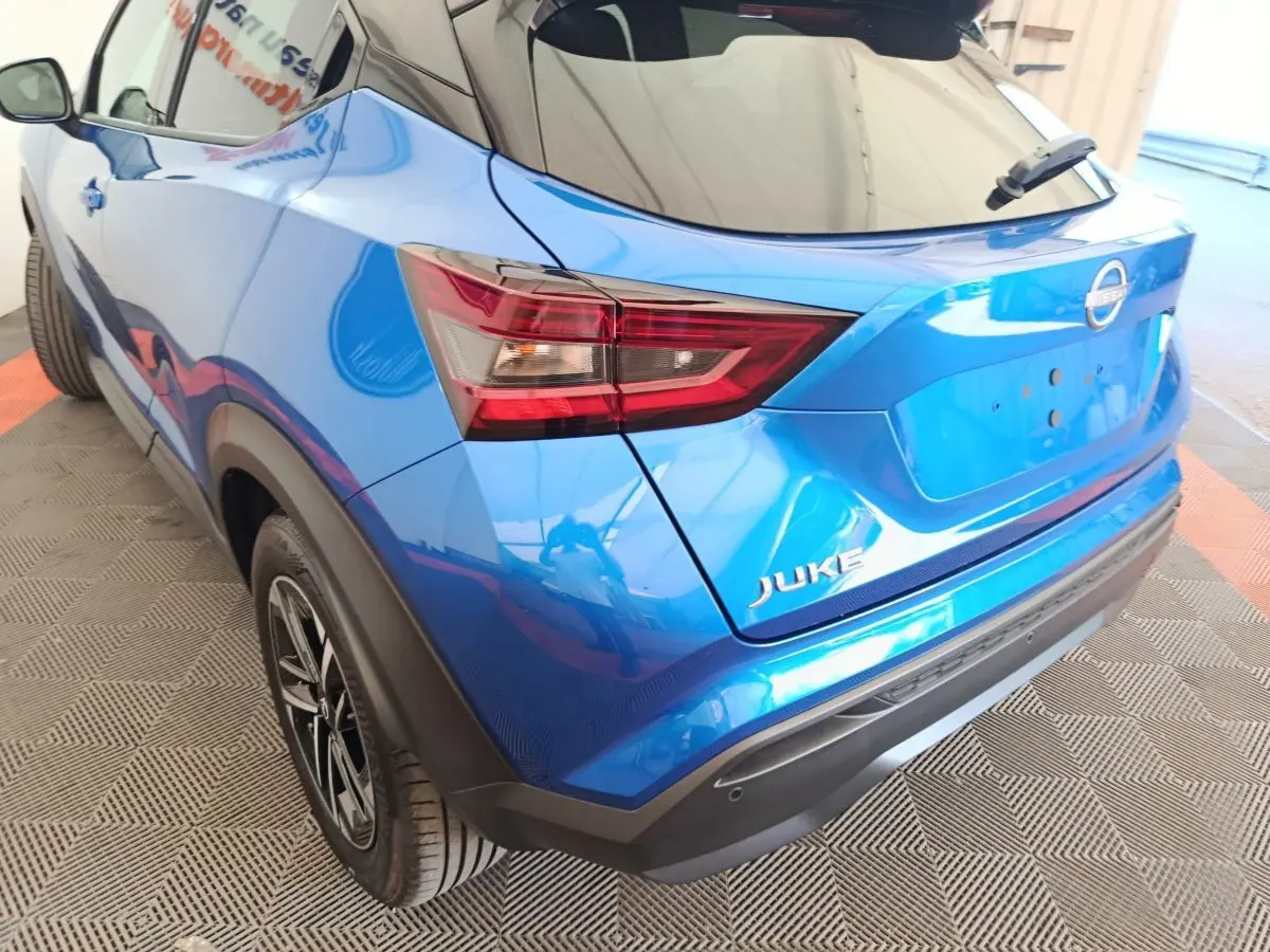 Vue 3/4 arrière droite du Nissan Juke bleu 2025 avec feux arrière LED et jantes alliage noires.