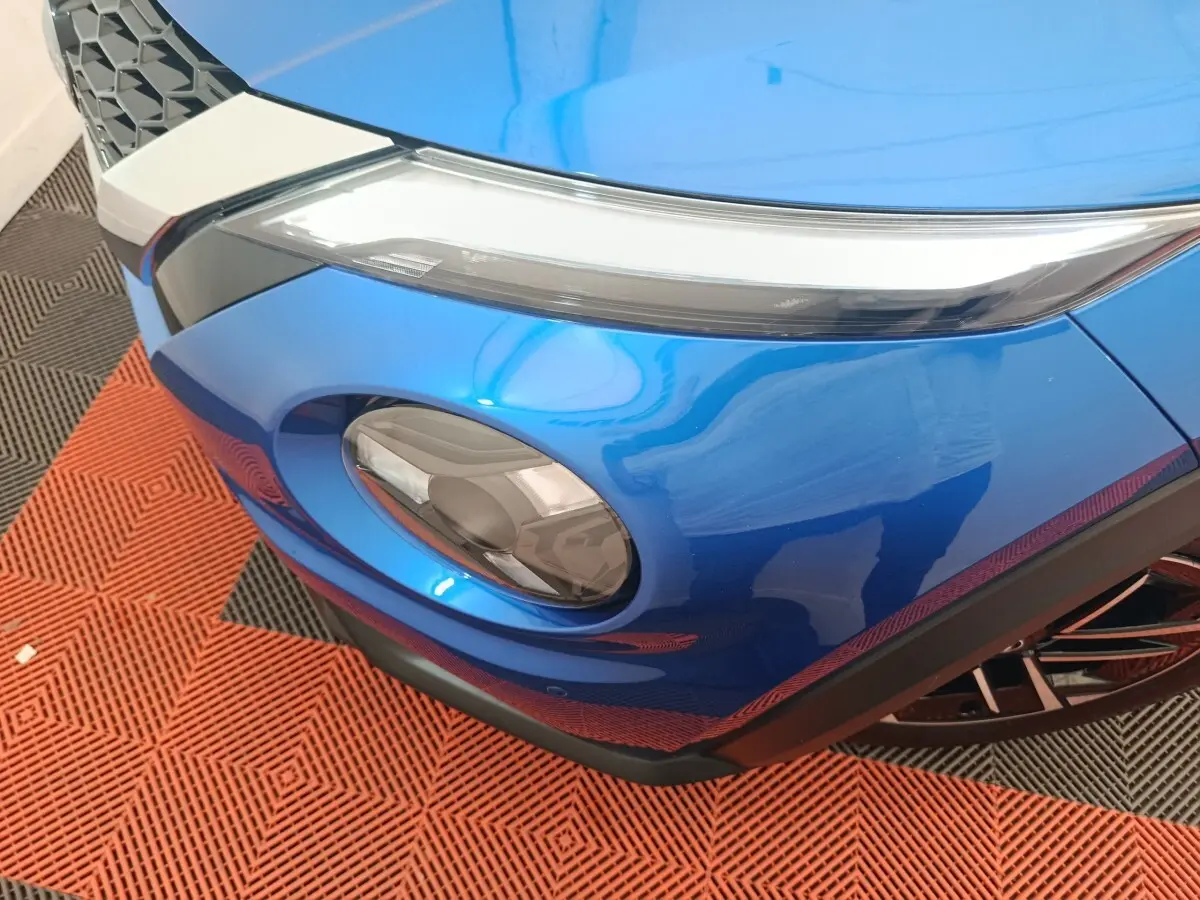 Gros plan sur le phare avant droit bleu du Nissan Juke 2025 avec partie supérieure fine et rondeur inférieure.