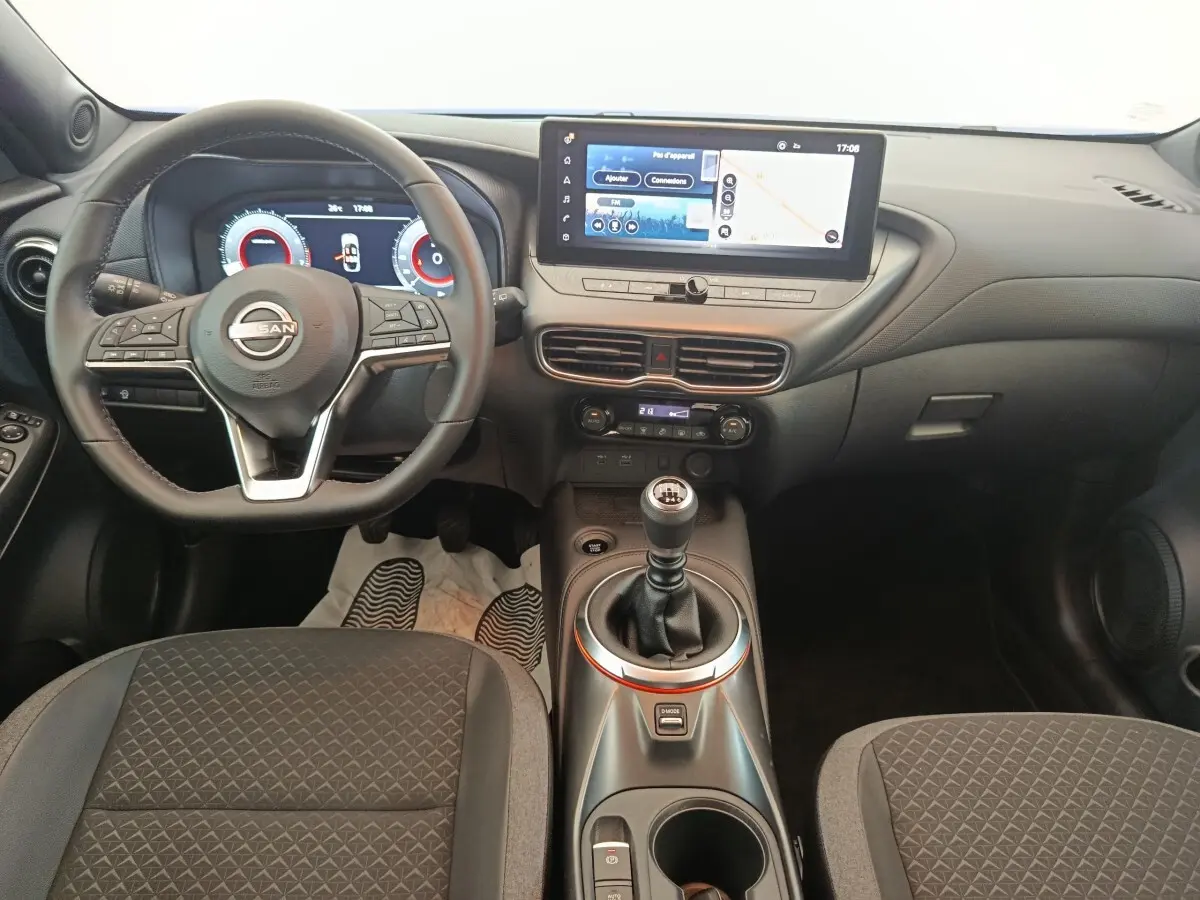 Intérieur noir du Nissan Juke 2025, vue de face sur le volant, tableau de bord digital et levier de vitesse manuel.
