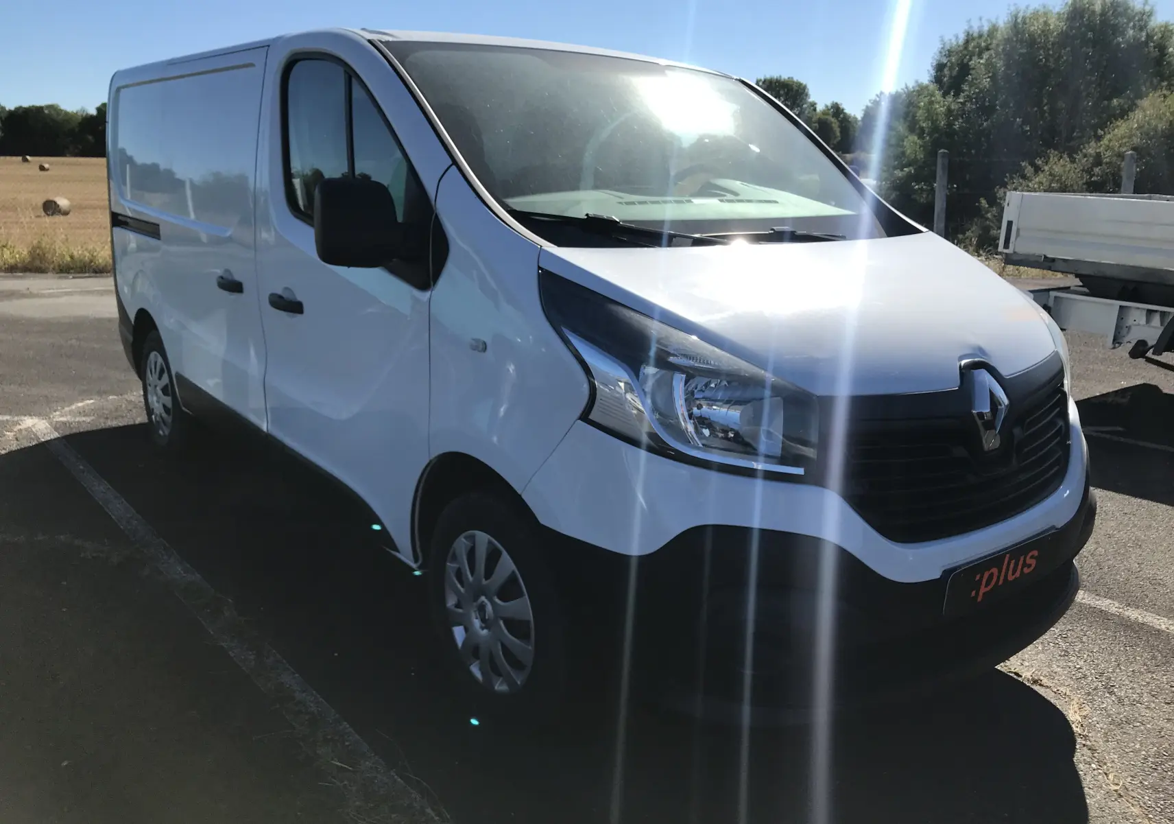 Renault Trafic Fourgon blanc vu en 3/4 avant droit, avec calandre noire et jantes acier, stationné en extérieur.
