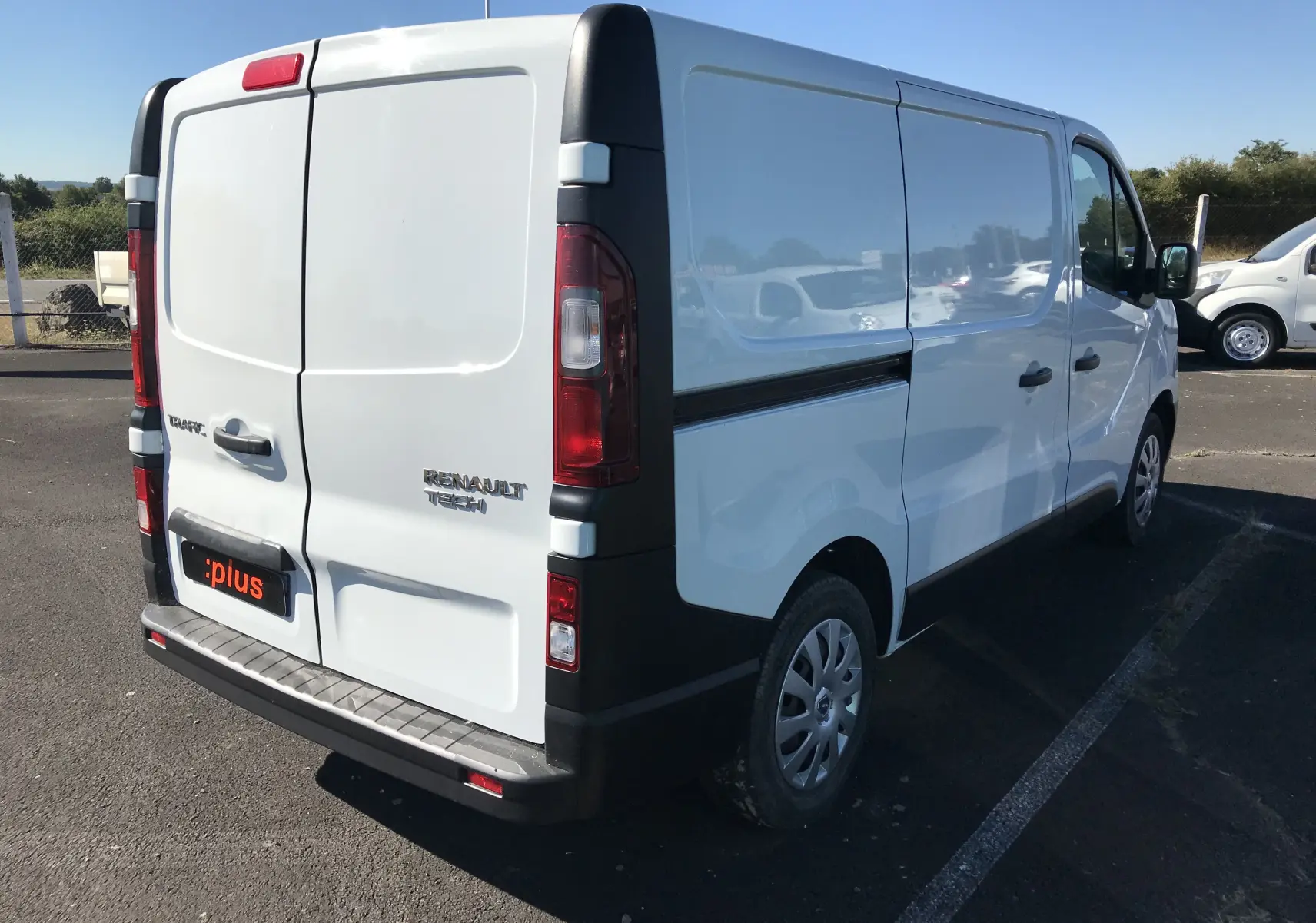 Vue 3/4 arrière droite d'un Renault Trafic Fourgon blanc 2017 avec portes arrière fermées et jantes acier.