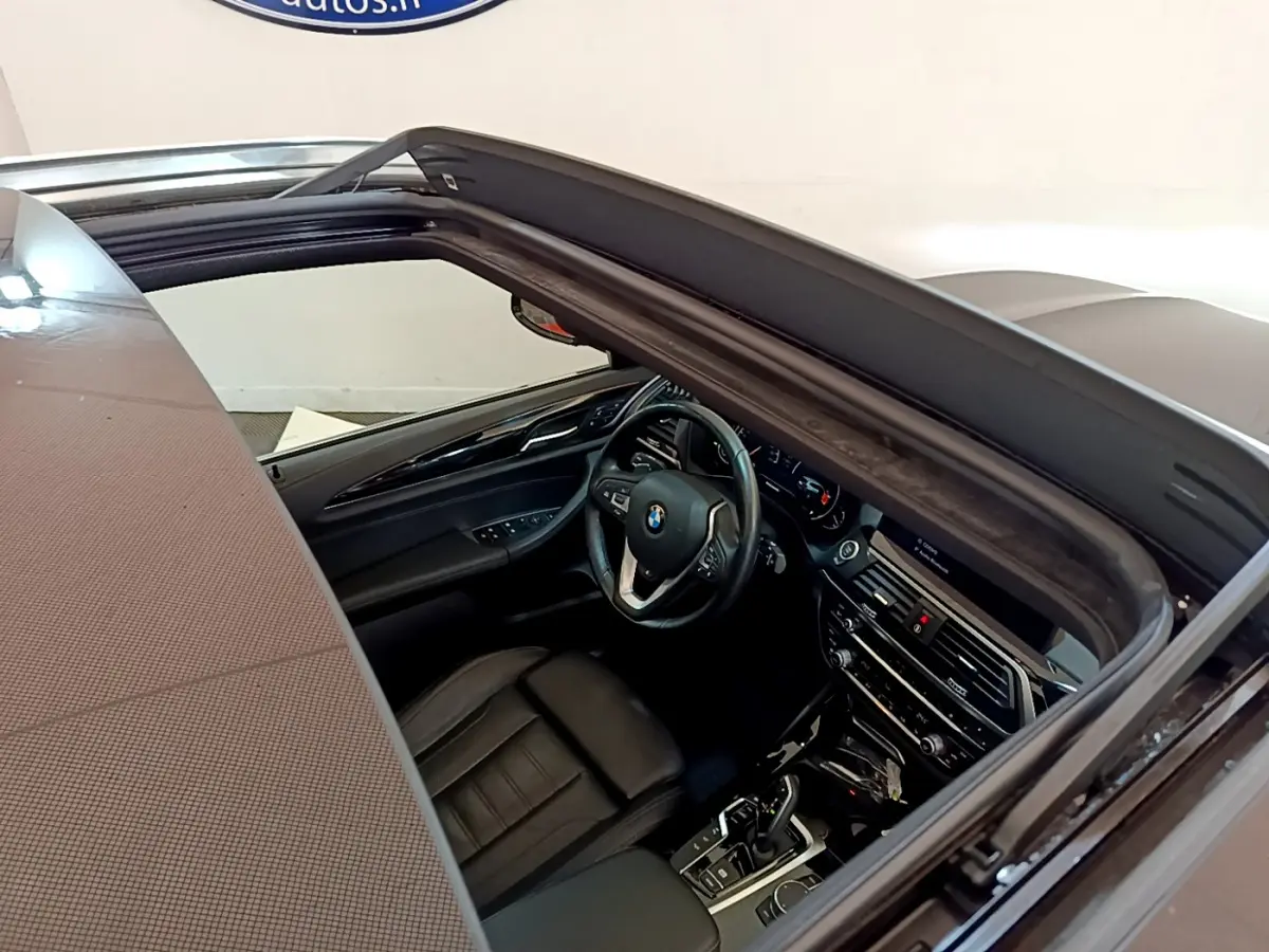 Vue intérieure par le toit ouvrant du BMW X3 noir, mettant en valeur le tableau de bord et le volant multifonctions.