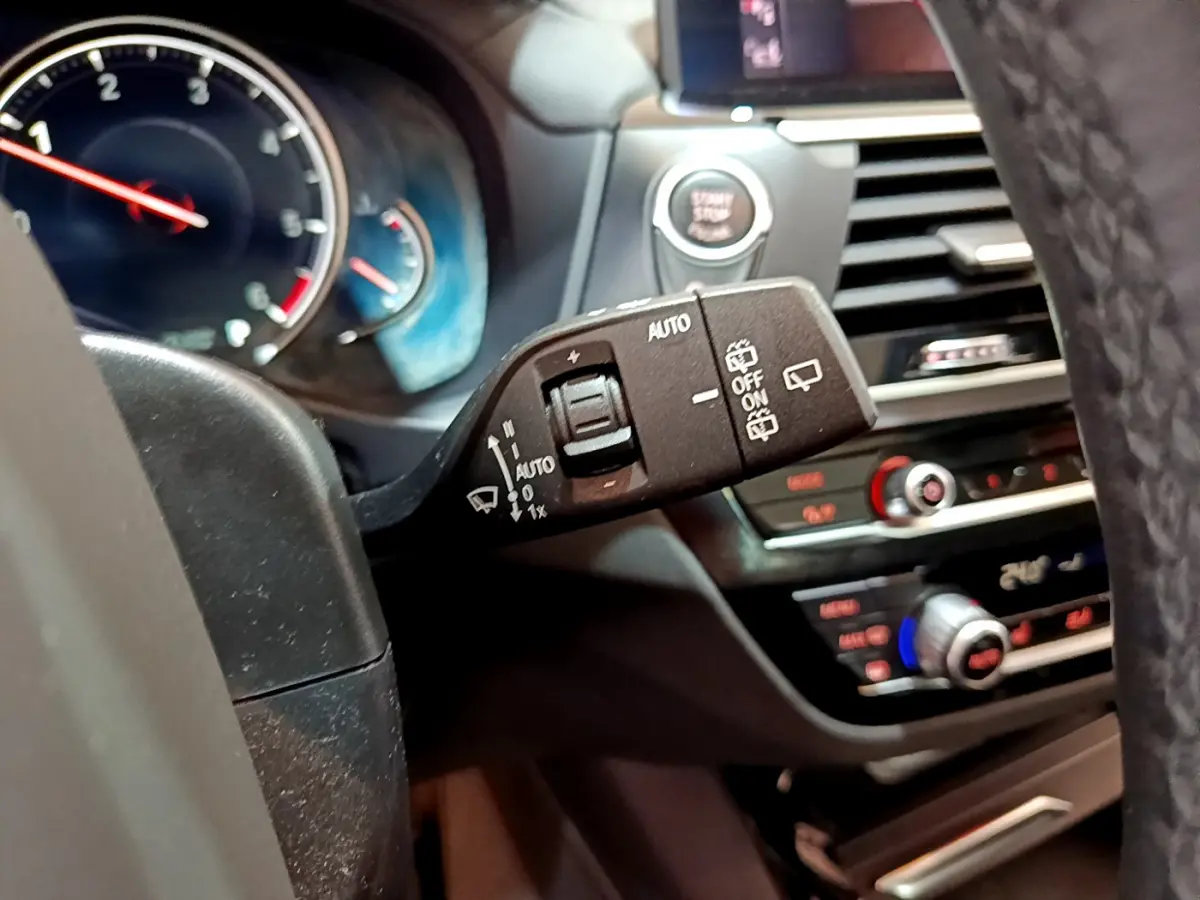 Gros plan sur la commande d’essuie-glace à gauche du volant dans l’habitacle noir du BMW X3 2019.