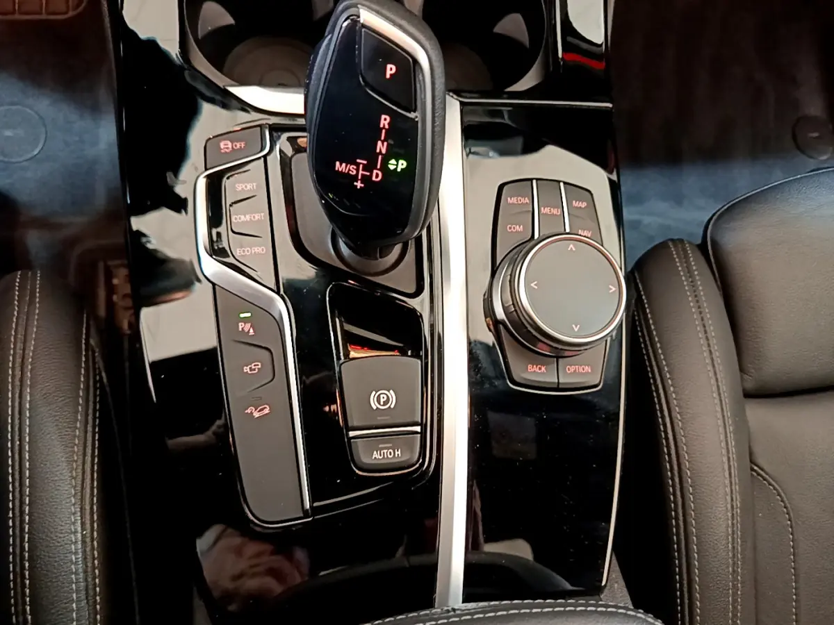 Gros plan sur la console centrale noire brillante du BMW X3 xDrive20d 2019 avec levier de vitesses et molette de commande.