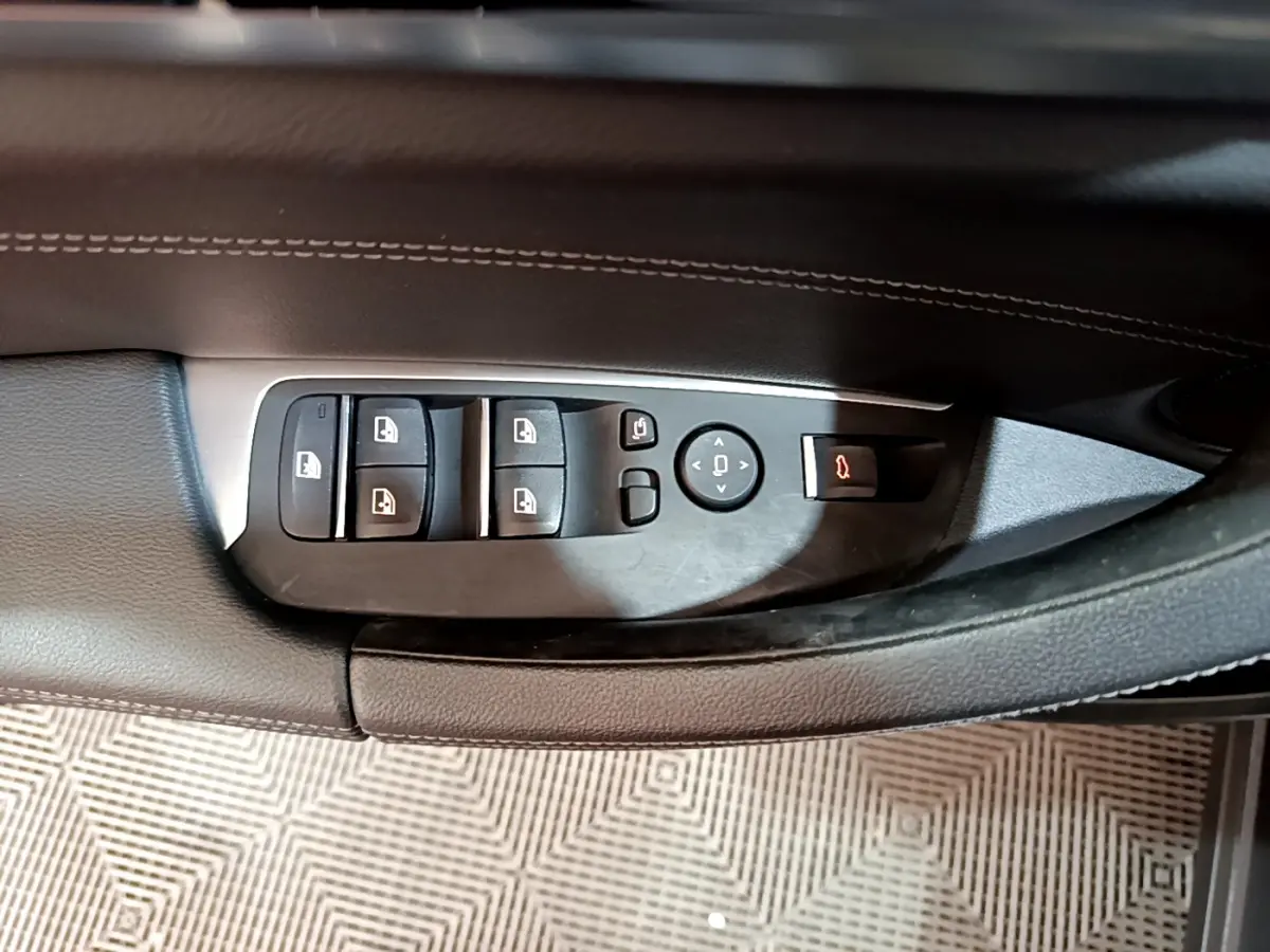 Gros plan sur les commandes de lève-vitres et rétroviseurs côté conducteur du BMW X3 noir 2019 Luxury.