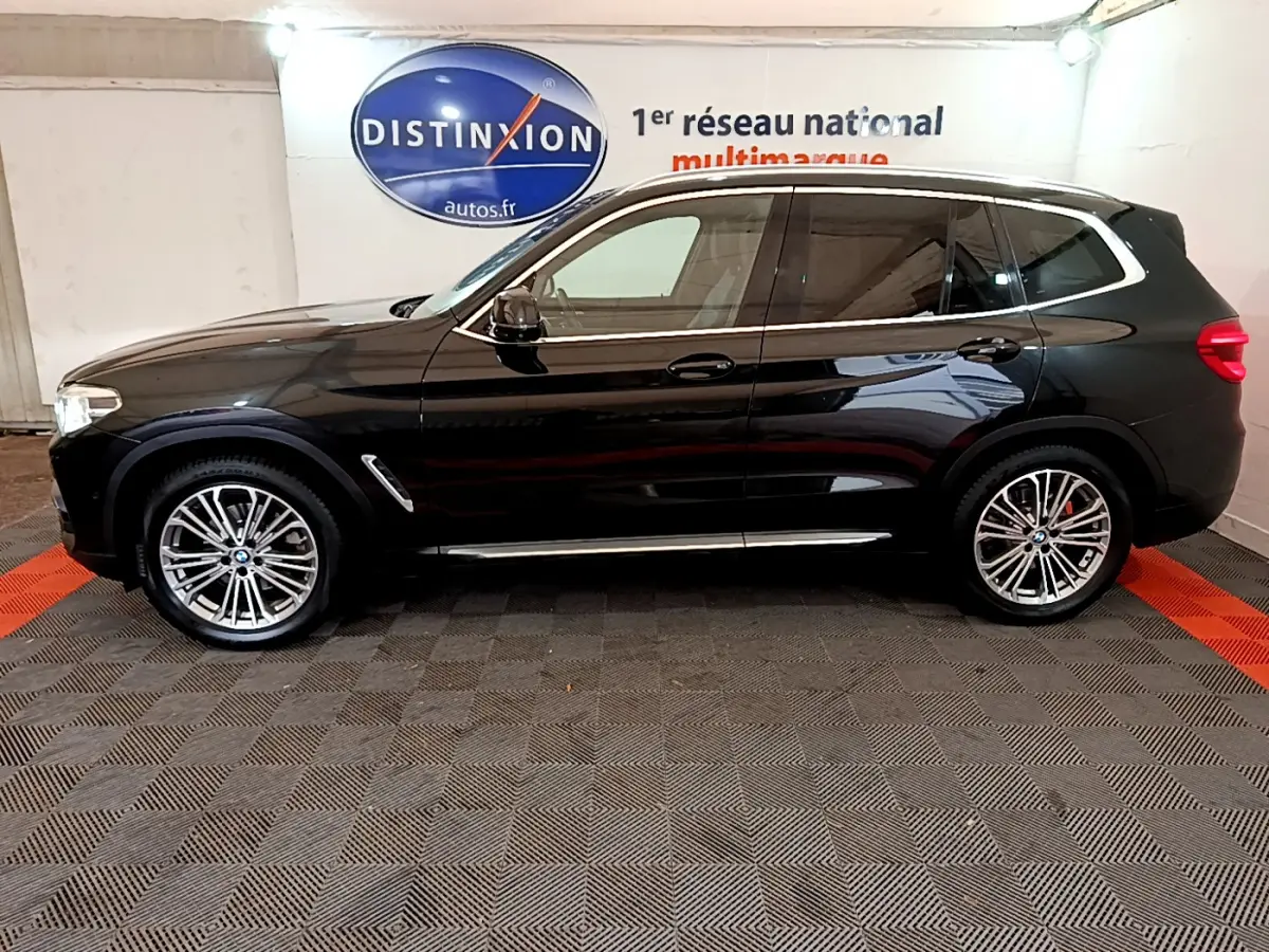 BMW X3 xDrive20d noir vu de profil côté gauche, avec jantes alliage et vitres teintées dans un showroom.