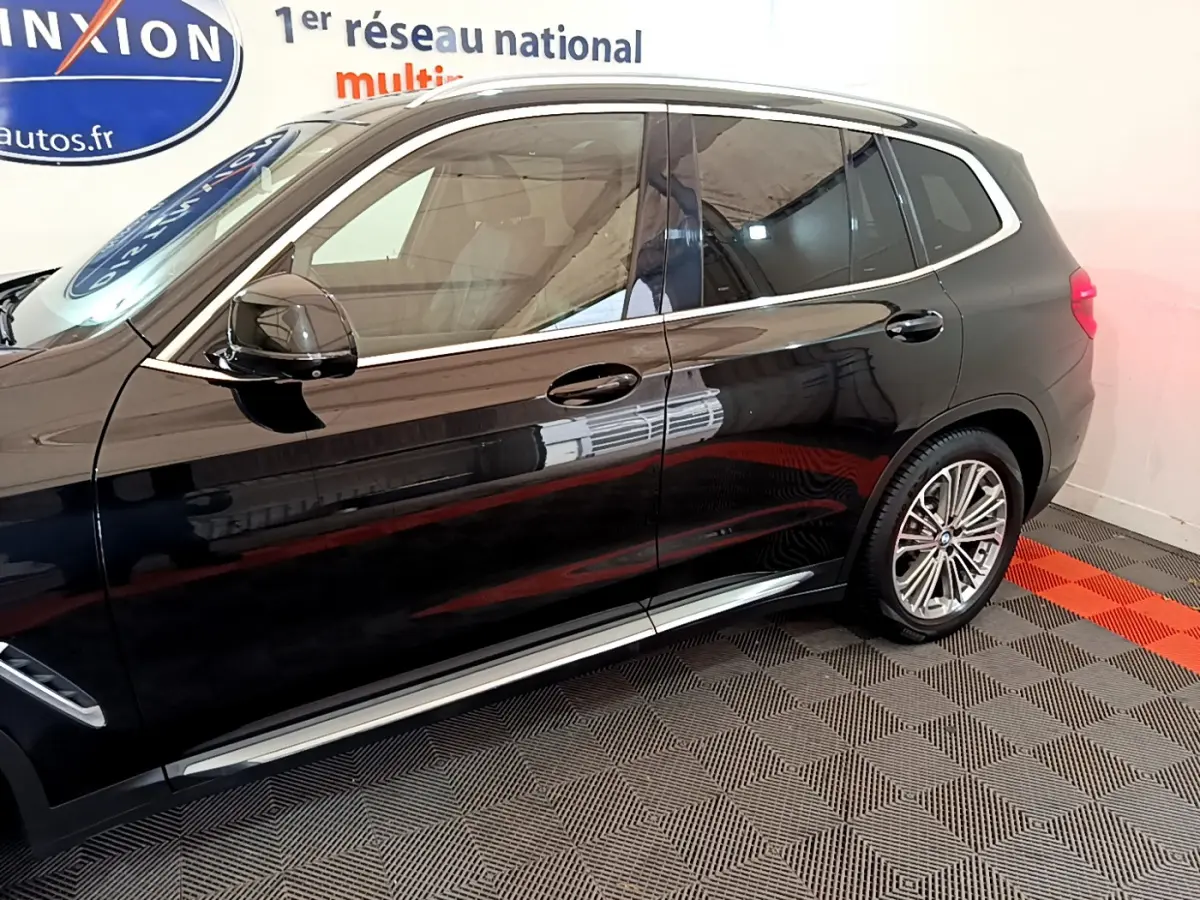 Profil côté gauche d'un BMW X3 noir 2019 avec jantes alliage et vitres teintées dans un showroom.