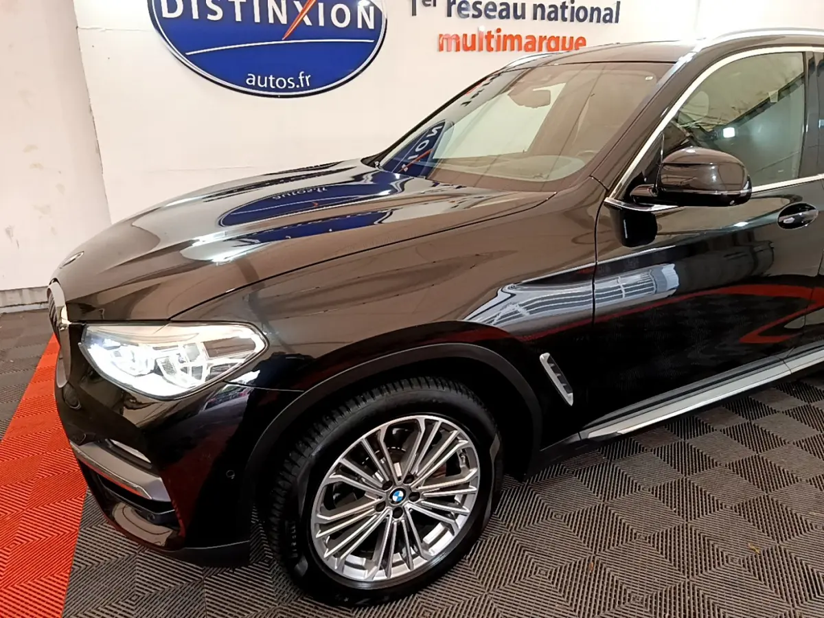 BMW X3 xDrive20d noir vu de 3/4 avant droit avec jantes alliage et phares LED allumés
