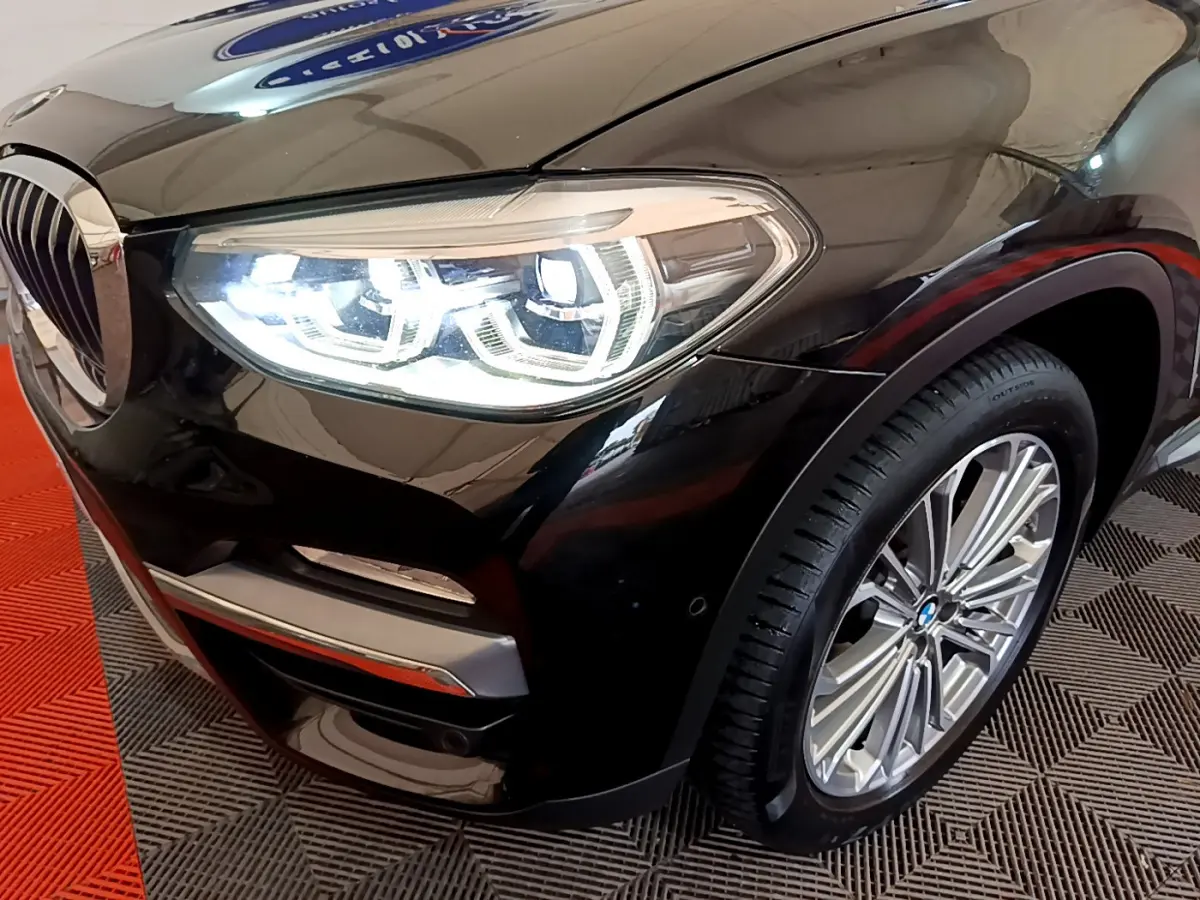 Gros plan sur l'avant droit noir d'un BMW X3 2019, mettant en valeur le phare LED et la jante alliage.