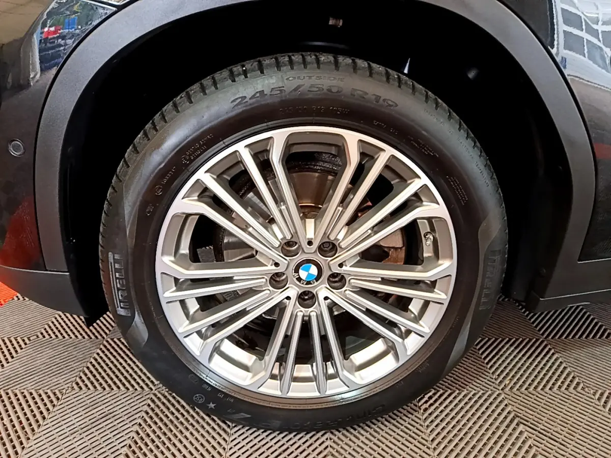 Gros plan sur la roue avant droite du BMW X3 noir, mettant en valeur la jante alliage multi-branches et le pneu Pirelli.
