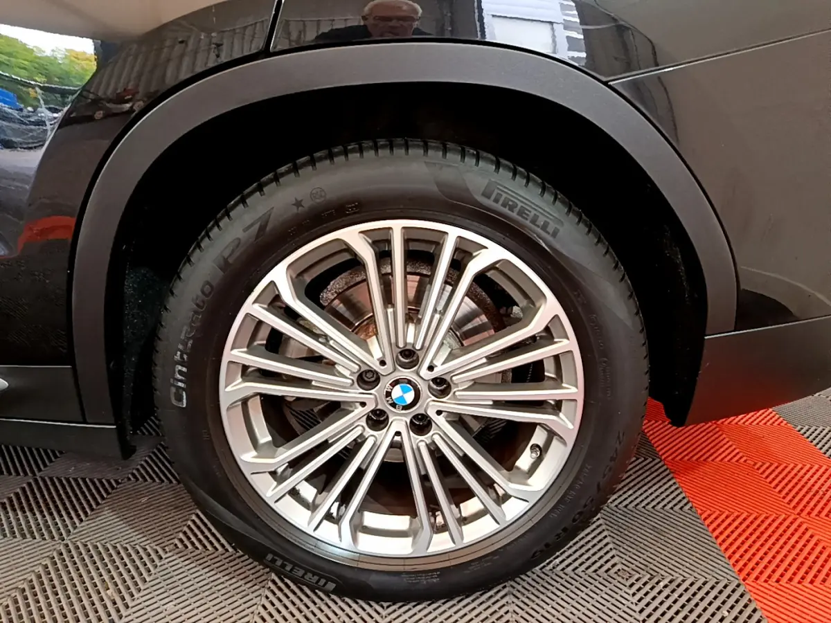 Gros plan sur la roue avant gauche du BMW X3 noir, mettant en valeur la jante alliage et le pneu Pirelli.