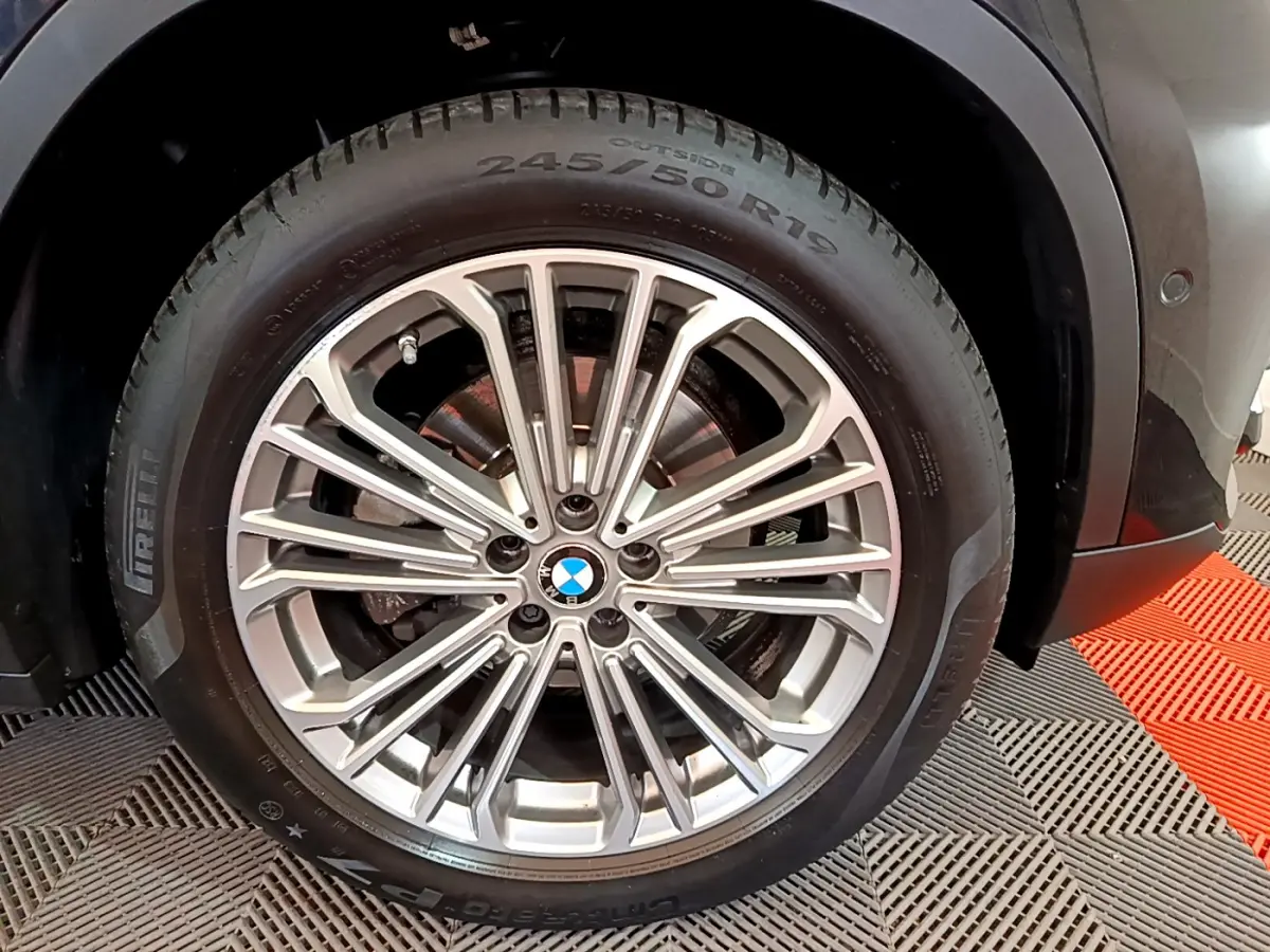 Gros plan sur la jante alliage argentée et pneu Pirelli du BMW X3 noir, roue avant droite visible.