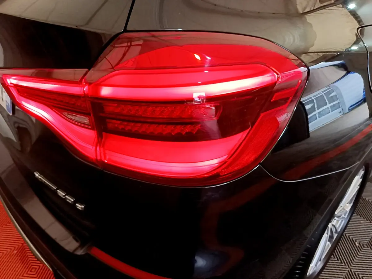 Gros plan sur le feu arrière droit rouge d’un BMW X3 noir 2019, soulignant la finition xDrive20d Luxury.