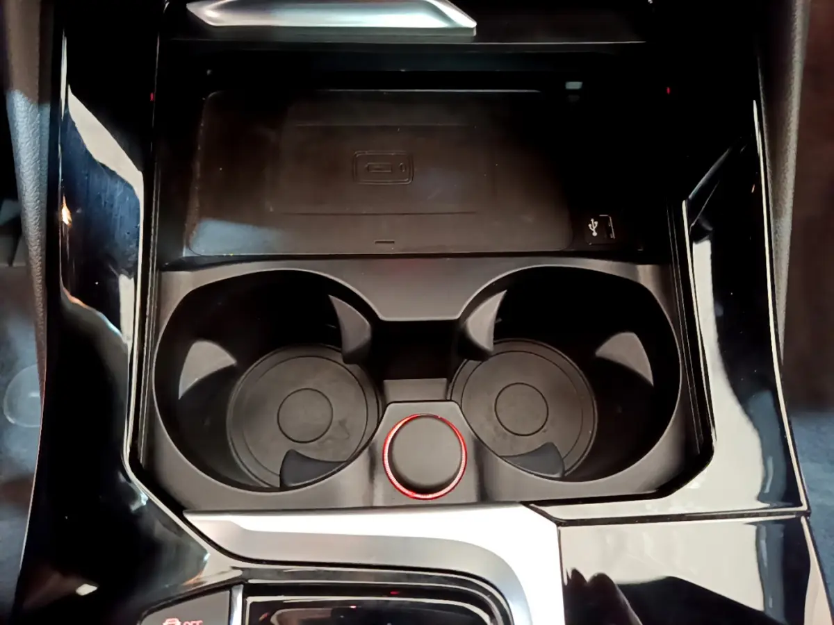 Gros plan sur la console centrale noire du BMW X3 xDrive20d 2019, avec porte-gobelets et molette rouge.