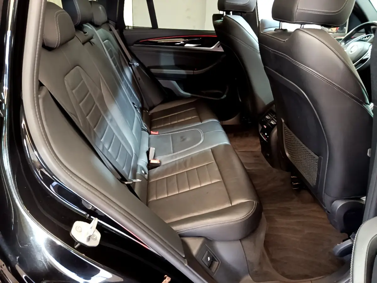 Vue intérieure côté gauche des sièges arrière en cuir noir du BMW X3 xDrive20d 2019 avec finitions élégantes et espace généreux.