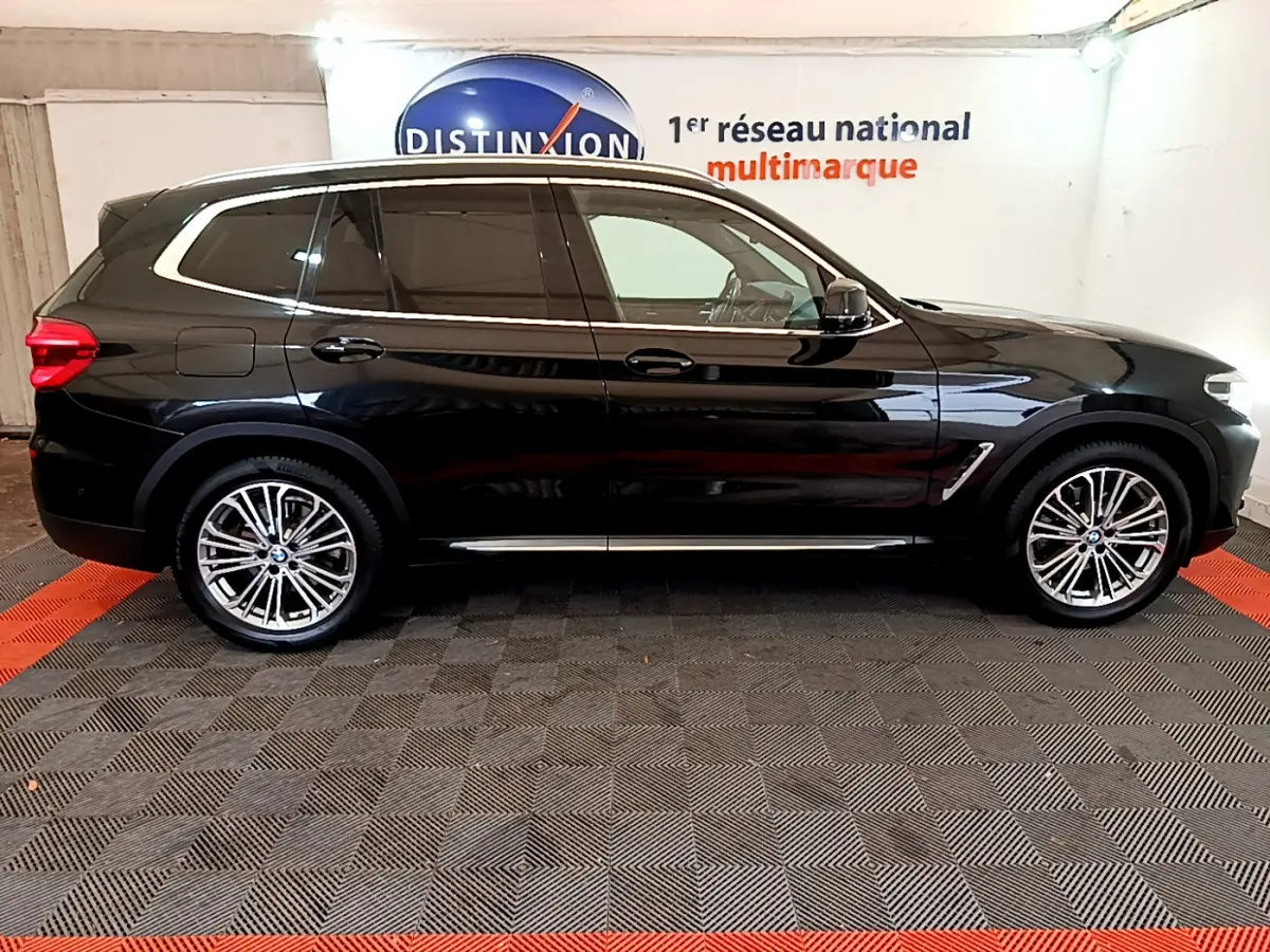 Profil côté droit d'un BMW X3 noir 2019 avec jantes alliage et vitres teintées dans un showroom intérieur.