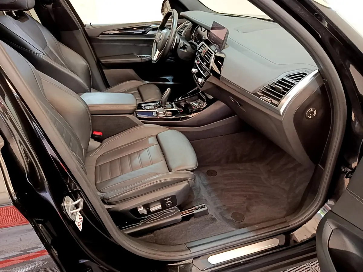 Intérieur noir du BMW X3 xDrive20d 2019 vu côté passager avant, avec sièges cuir et tableau de bord moderne.