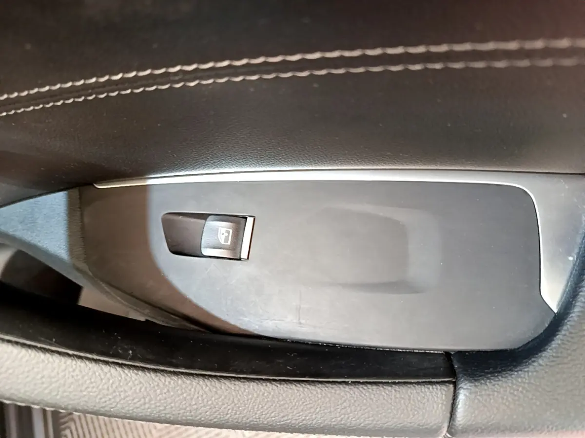 Gros plan sur le bouton de commande de lève-vitre côté conducteur dans l'intérieur noir du BMW X3 xDrive20d 2019.