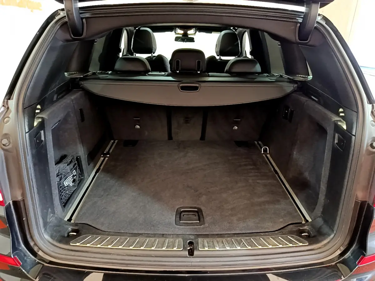 Coffre ouvert d'un BMW X3 noir 2019, vue arrière montrant l'espace de chargement et la tablette cache-bagages.