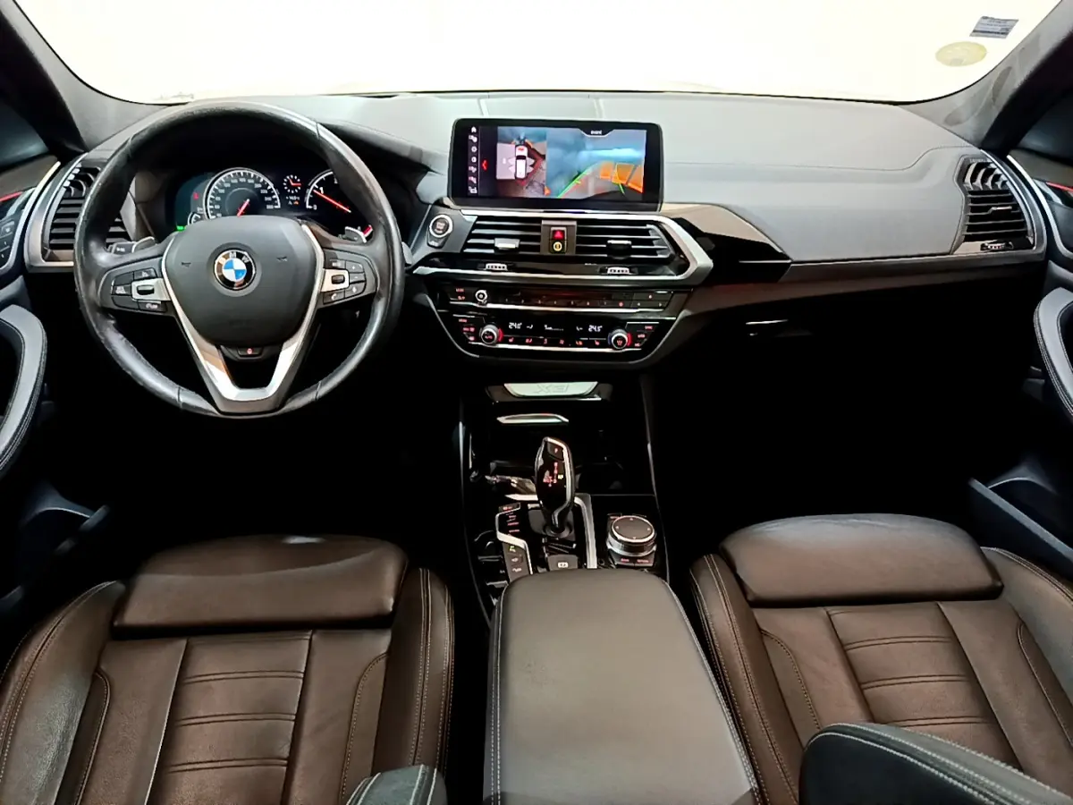 Intérieur noir de BMW X3 2019 vu de face, tableau de bord avec écran tactile 10,3 pouces et volant multifonctions.