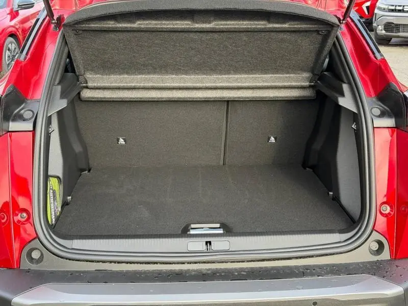 Vue arrière du coffre ouvert d'un Peugeot 2008 rouge, montrant l'espace de chargement vide et la tablette cache-bagages.