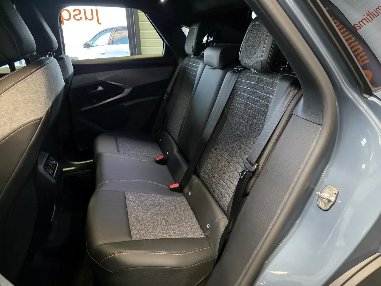 Vue intérieure côté droit sur la banquette arrière en tissu gris et cuir noir du Peugeot 3008 bleu clair 2025.