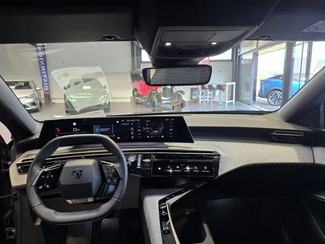Vue intérieure du tableau de bord et volant cuir noir du Peugeot 3008 hybride 2025, avec écran panoramique incurvé.