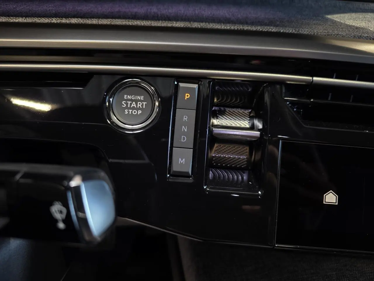 Gros plan sur la console centrale noire brillante du Peugeot 3008 2025 avec bouton start/stop et commandes de boîte auto.