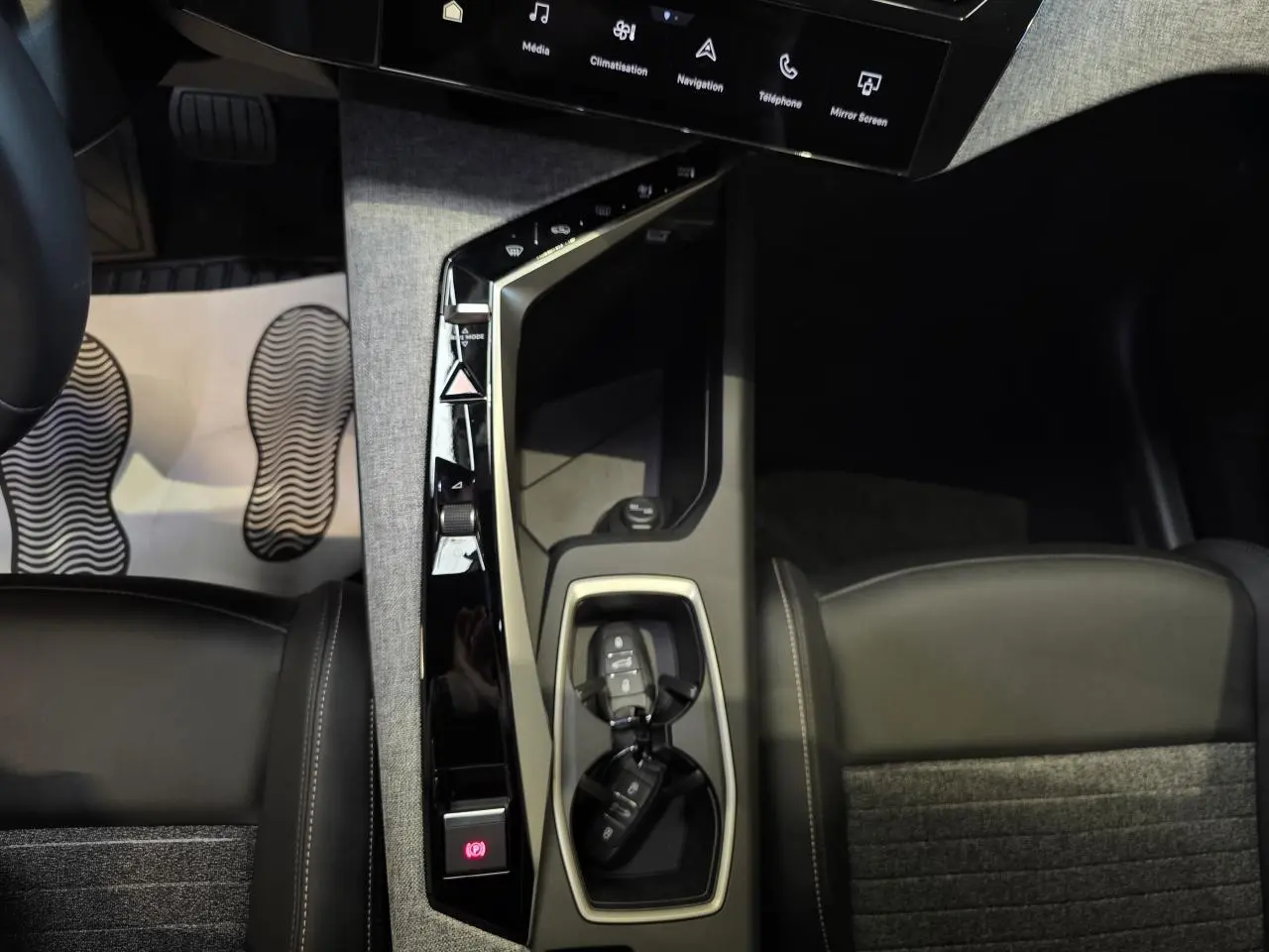Vue rapprochée de la console centrale du Peugeot 3008 bleu clair 2025, avec clés et sellerie tissu gris foncé.