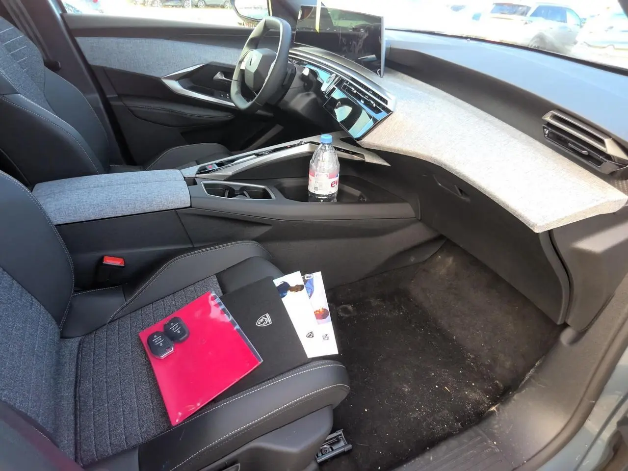Intérieur avant droit du Peugeot 3008 2025, tableau de bord clair avec écran incurvé et sièges tissu gris foncé.
