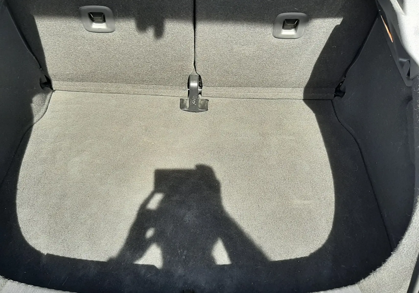 Vue plongeante sur le coffre vide tapissé de tissu gris clair du Volkswagen New Beetle noir de 2015.