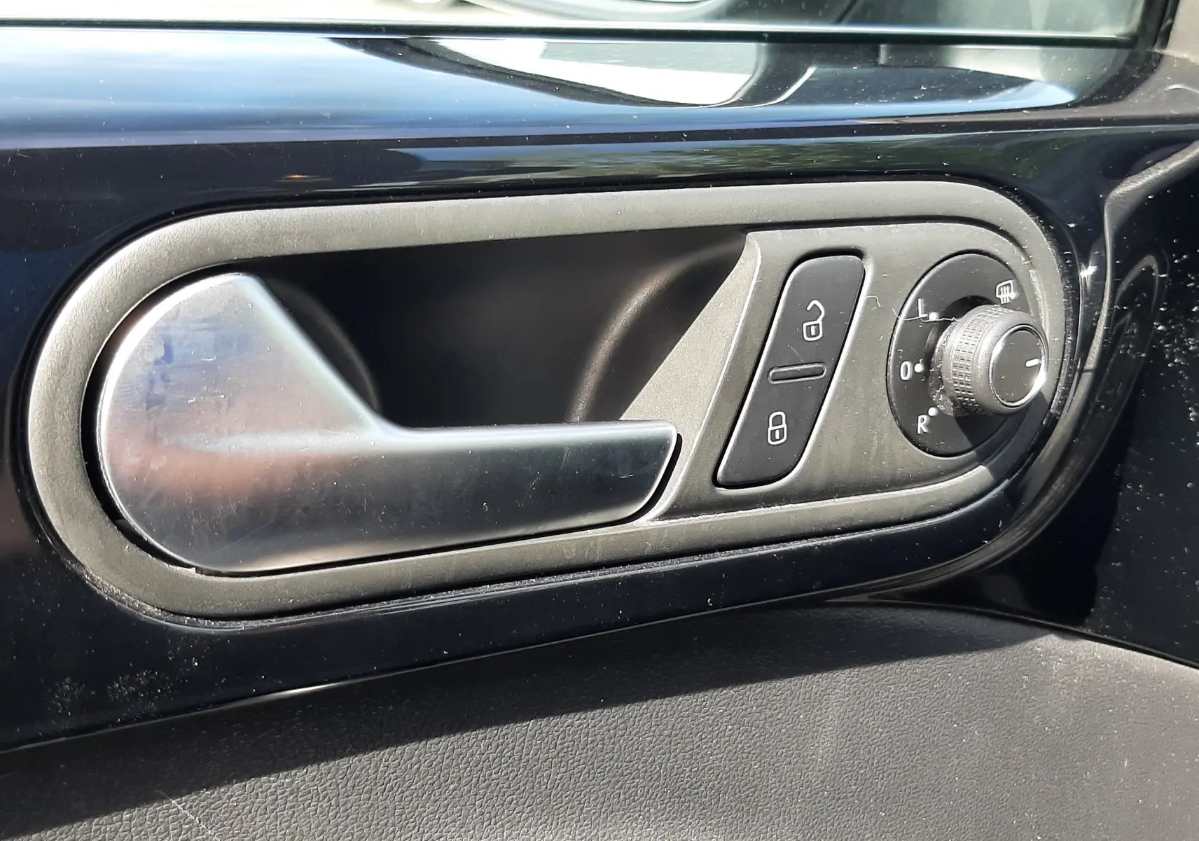 Poignée de porte intérieure noire avec commandes de verrouillage et réglage des rétroviseurs du Volkswagen New Beetle 2015.